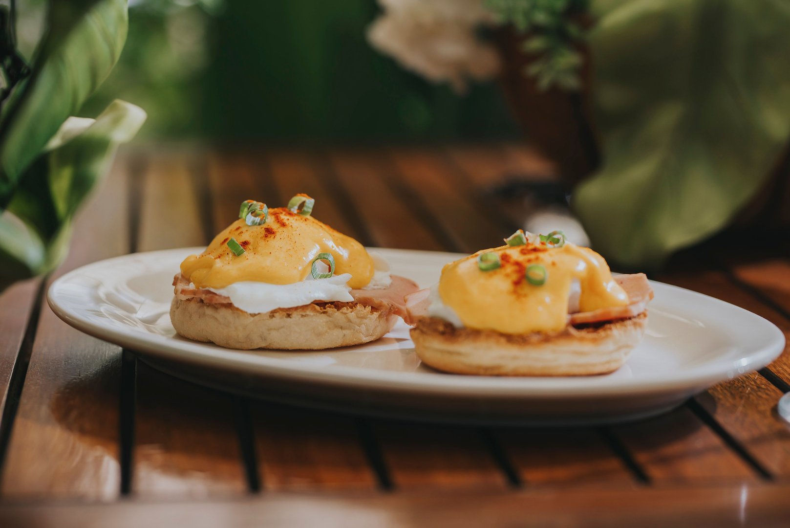 A delicious eggs benedict topped with hollandaise sauce and garnished with green onions