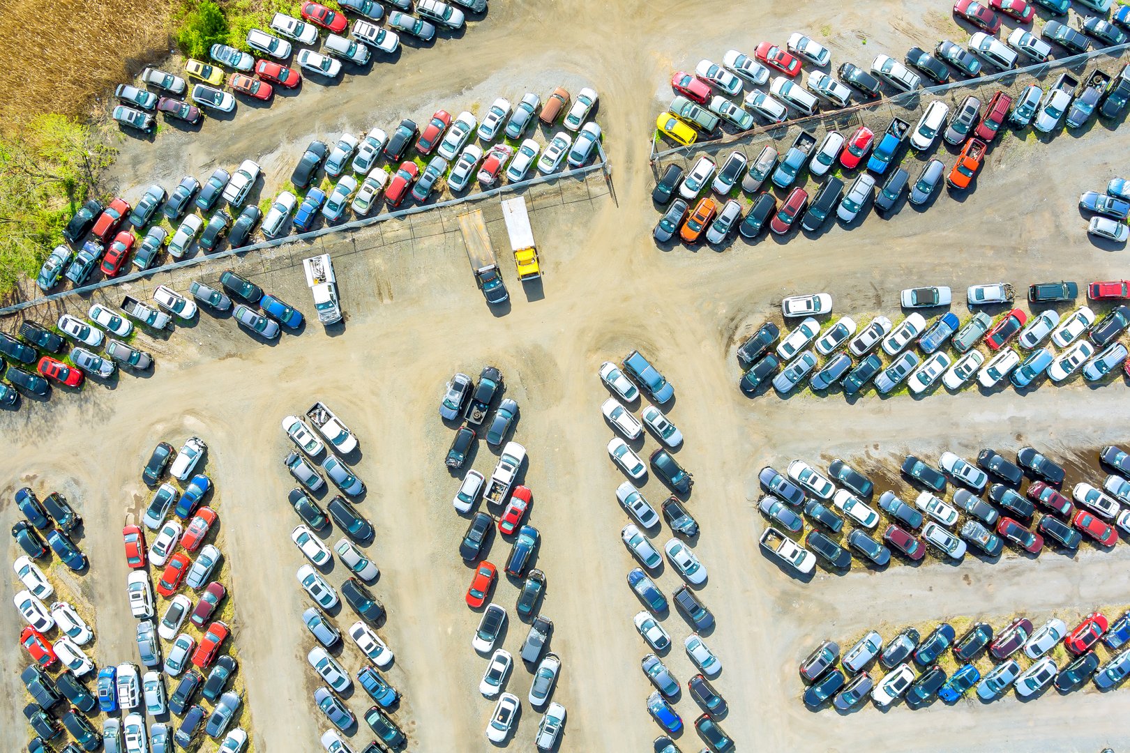 Countless cars trucks are parked closely together in large outdoor lot pre owned dealership