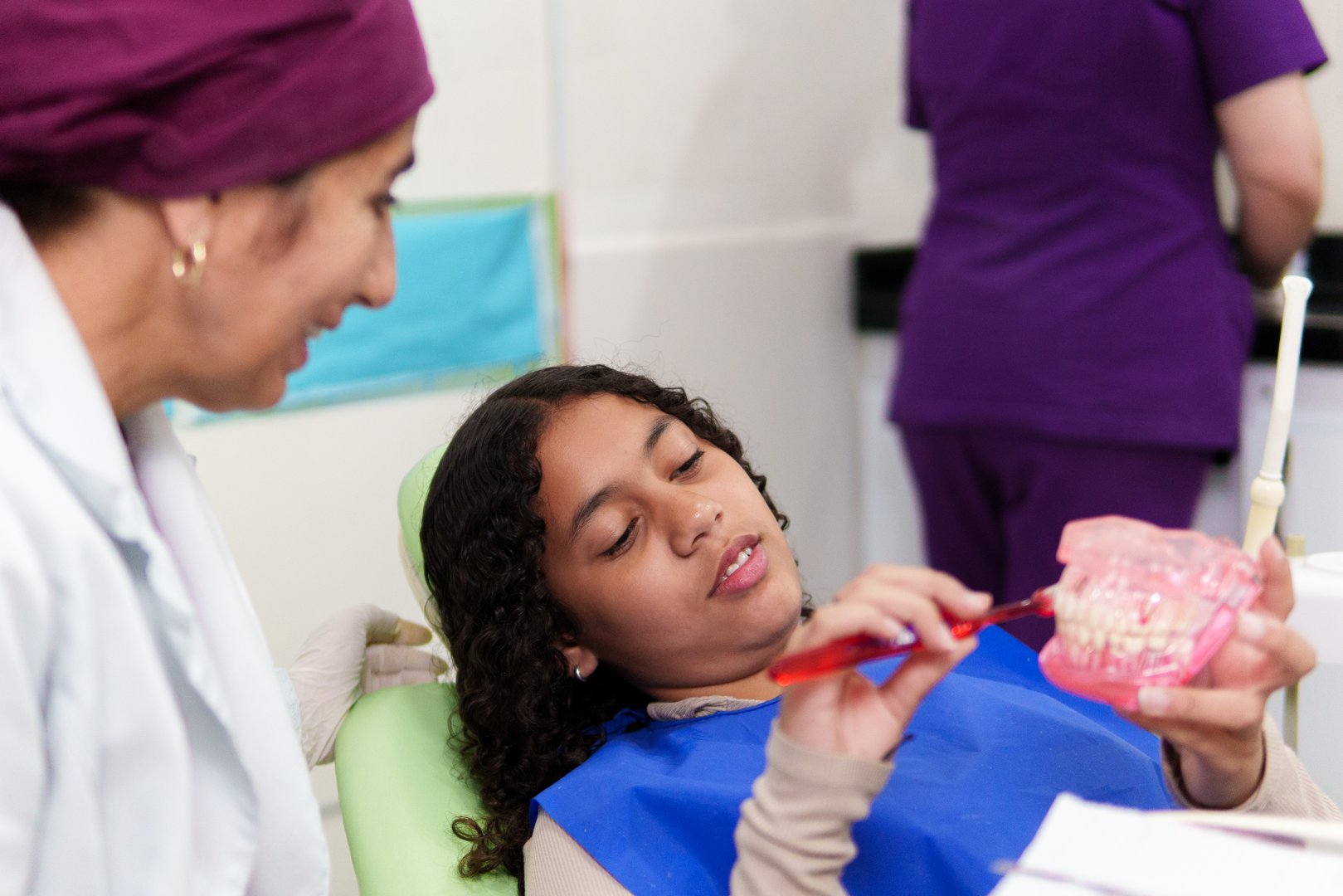Dentist showing a young girl how to correctly brush her teeth using a dental mold and a toothbrush in a dental clinic