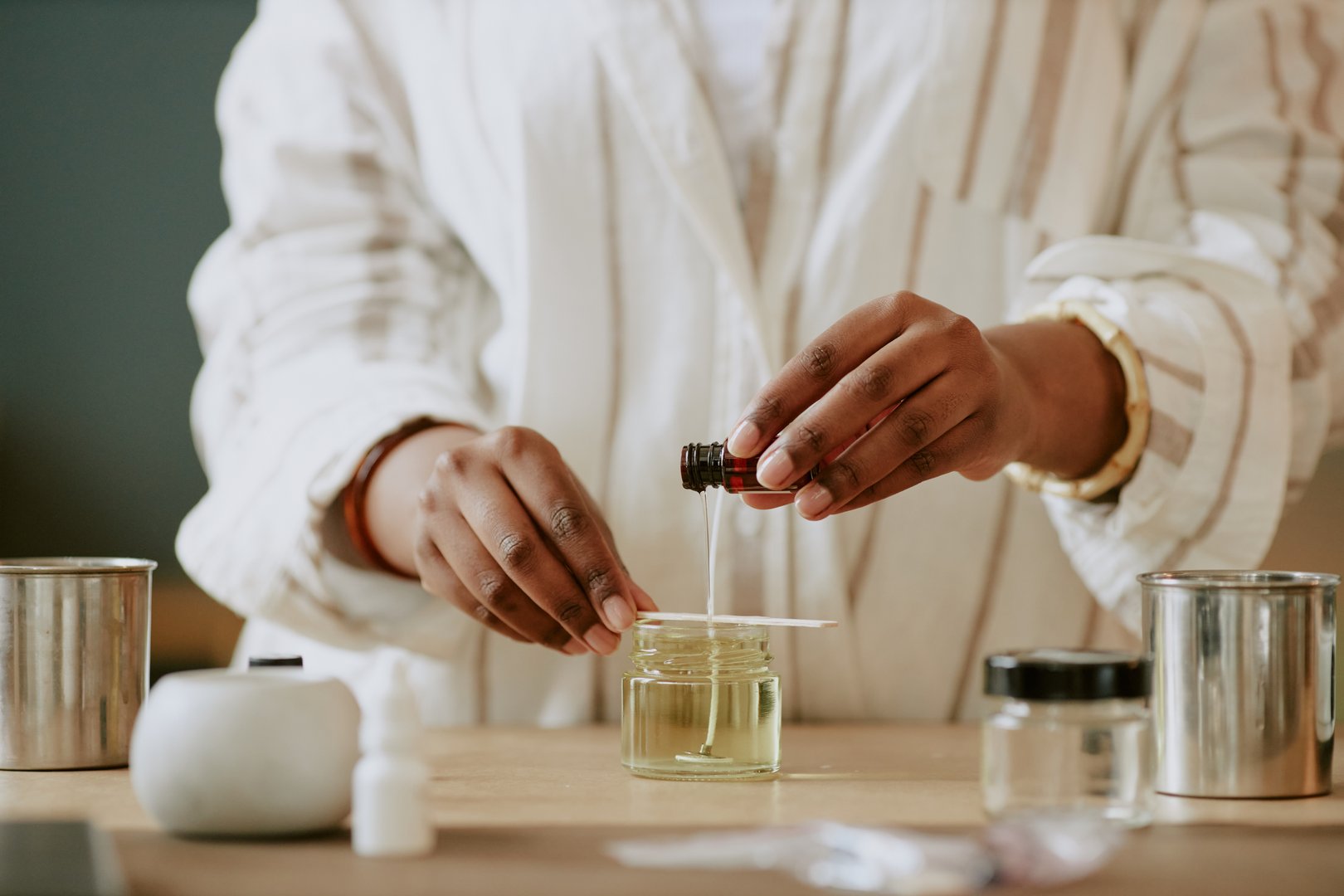 Pair of hands blending essential oils for perfume making in an artisan lab with various containers. Scene captures precision and dedication of the craft without revealing identity