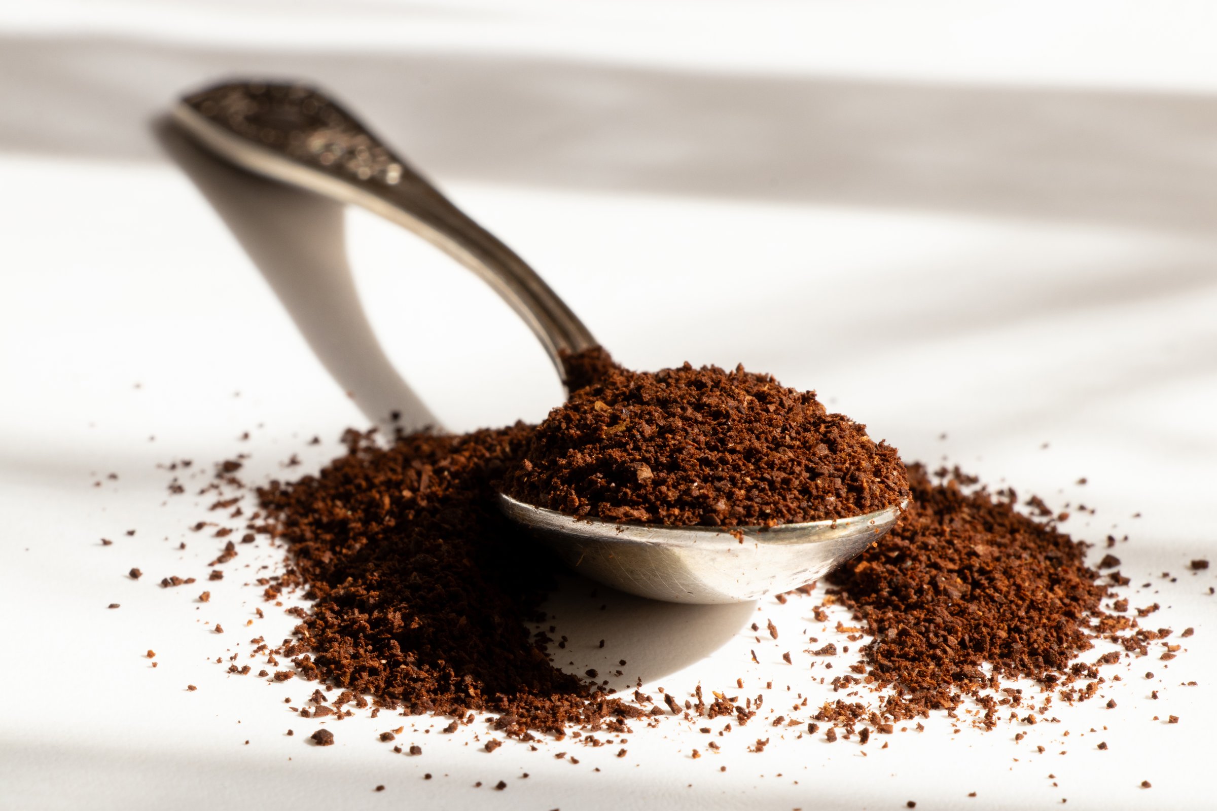 Old spoon with ground coffee in sunlight, aroma of the beginning of the day, scattered ground coffee