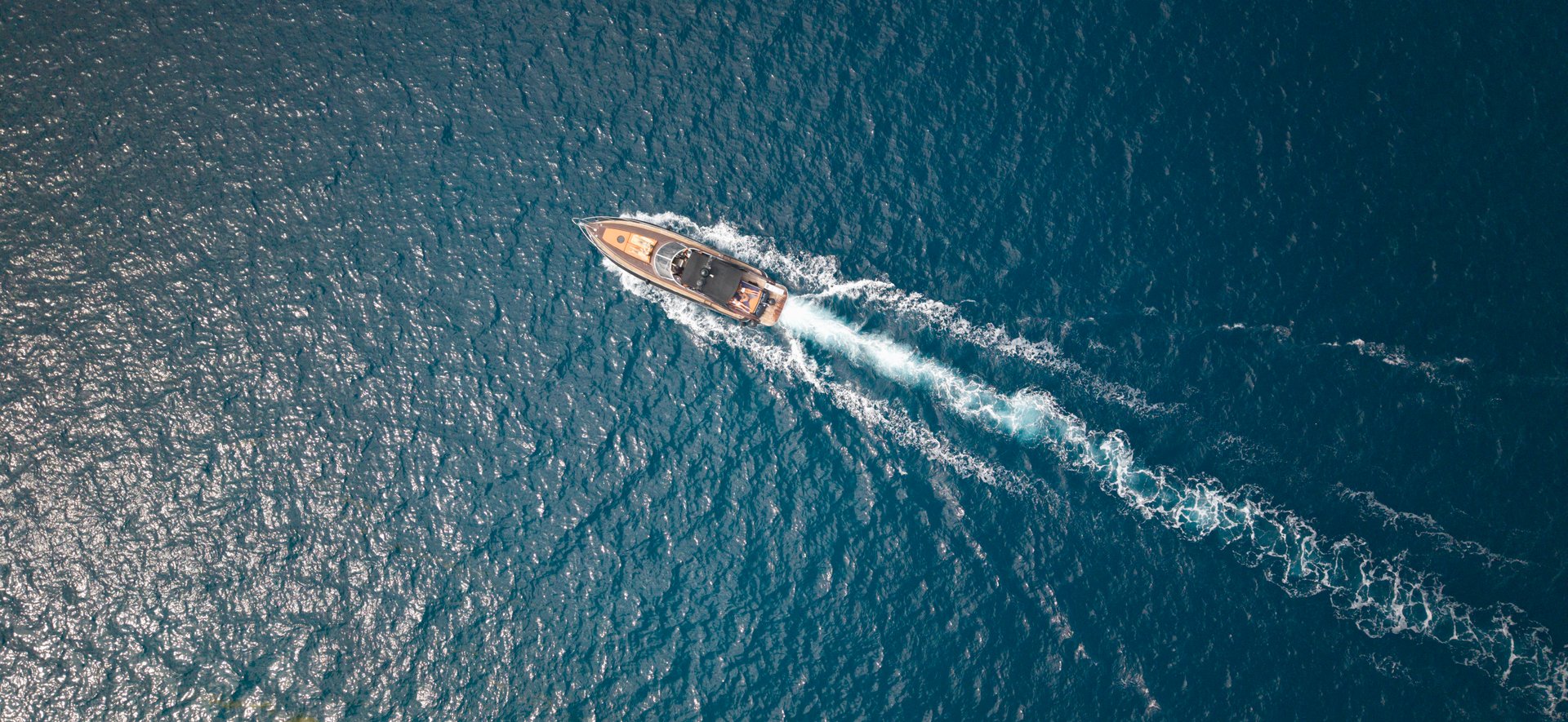 A stunning view of a luxury yacht cutting through the Mediterranean Sea, showcasing the vibrant blue waters. Aegina Egina Greece