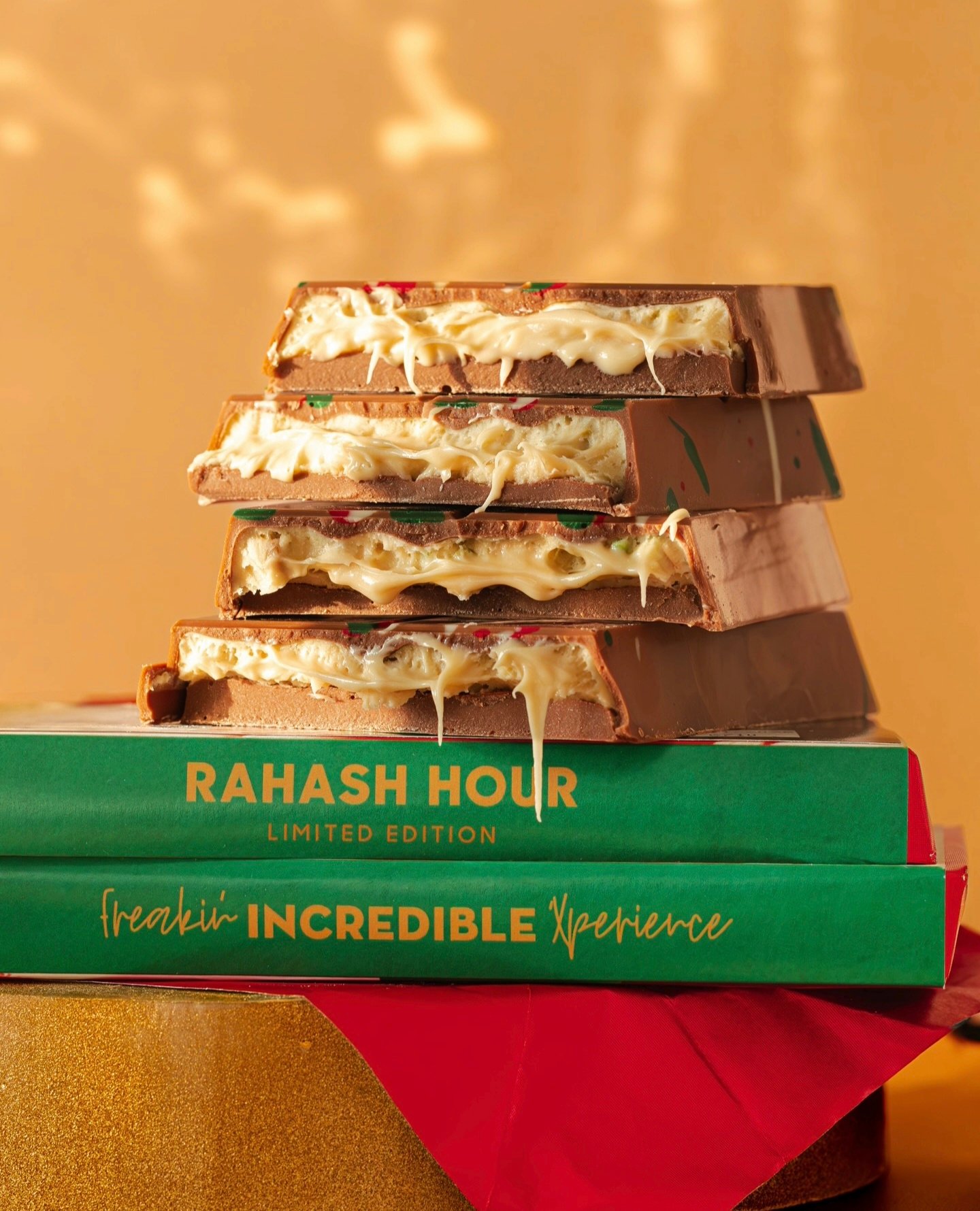 Single, premium, square chocolate praline in its open gold foil wrapper. Top down view, granite counter top background, close up, no people