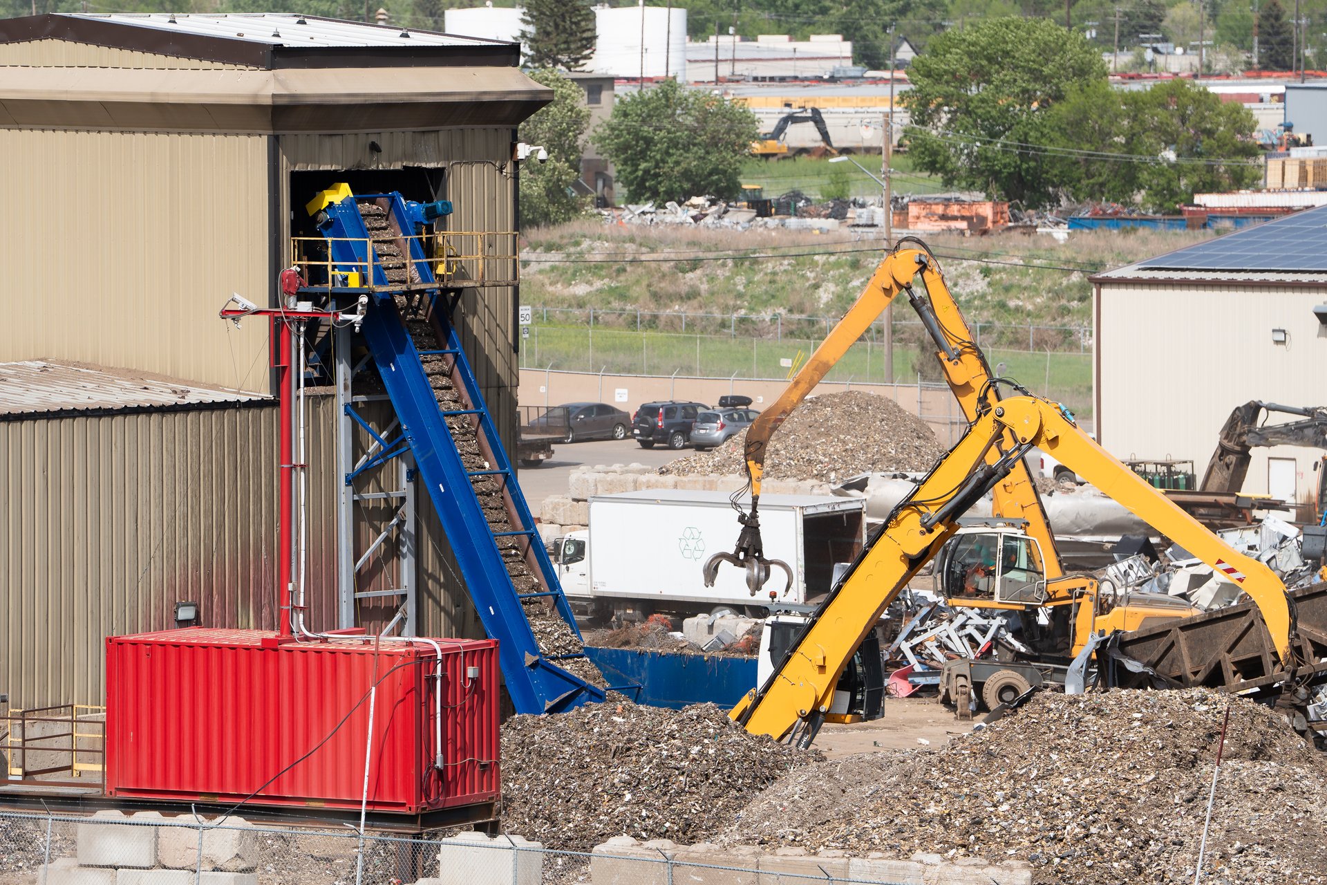 Machines sorting scrap metal at a recycling plant with conveyer belts in an industrial park.