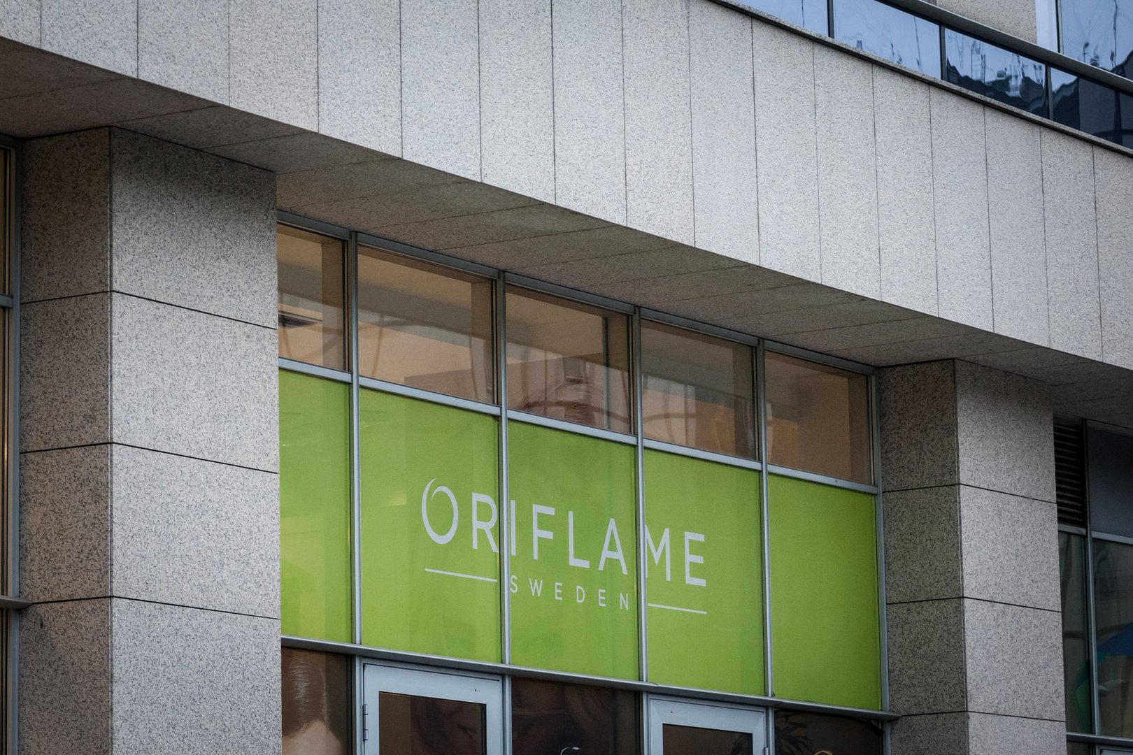Picture of a sign with the Oriflame logo taken on their main retailer for Belgrade, Serbia with sellers working in the background. Oriflame is Swedish cosmetics company selling personal care, accessories and nutritional products online and direct through a multi-level marketing model.