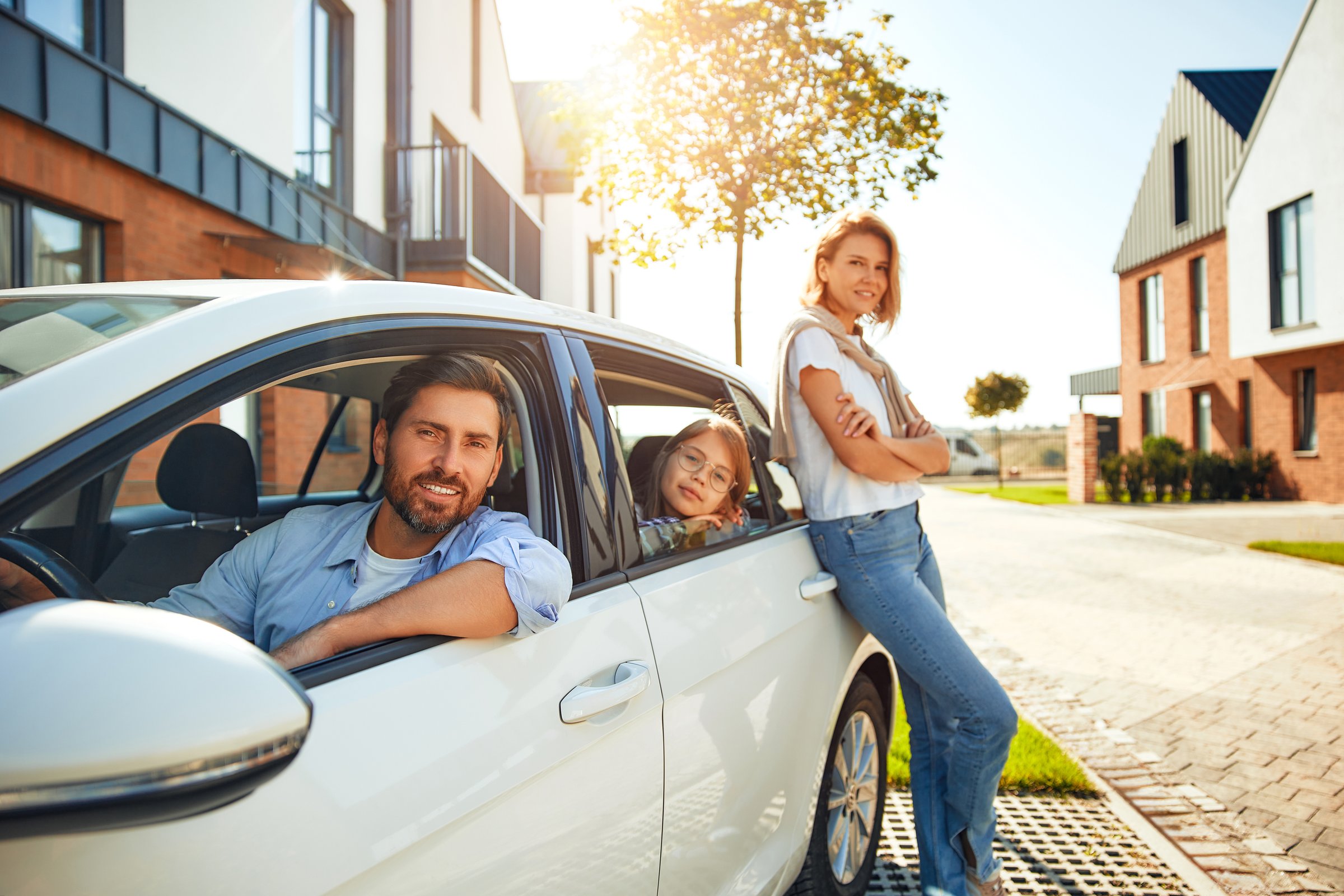 A young happy family with their daughter arrived by car to their new home