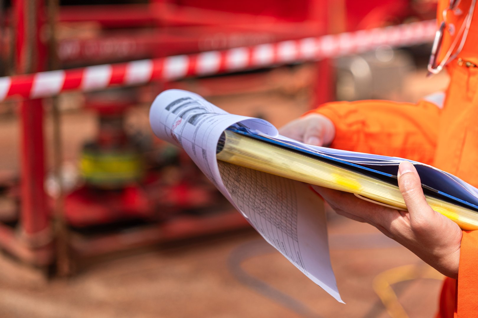 Action of a supervisor is checking on paperwork document during perform safety audit at operation work site. Industrial working scene, close-up and selective focus.