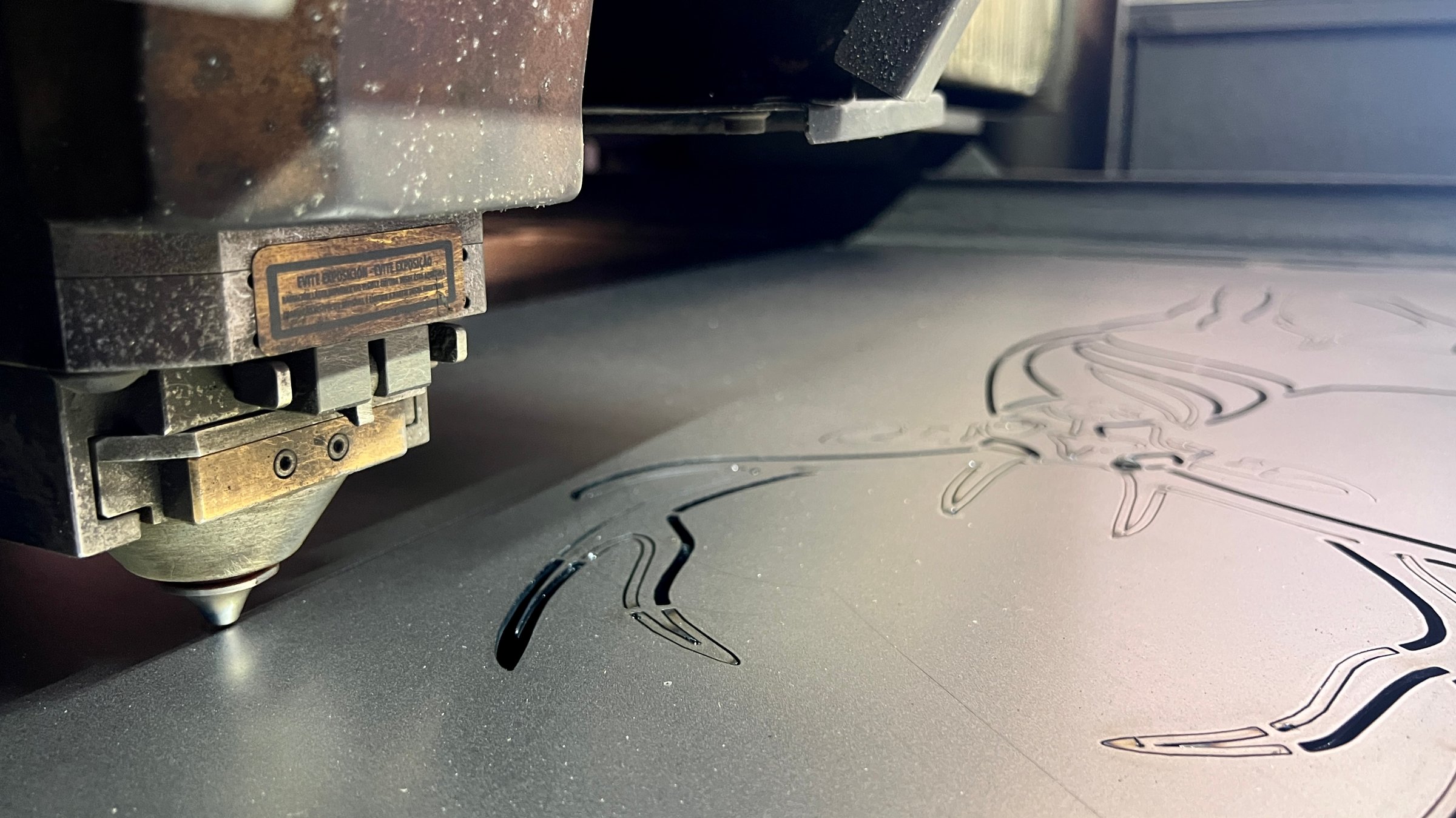 Industrial laser engraving intricate design into metal sheet, showcasing precision manufacturing process