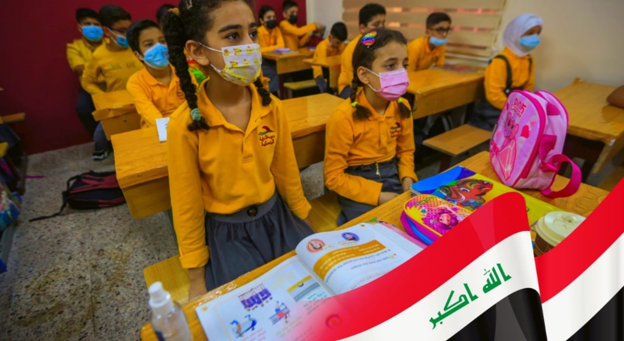 Children in a classroom wearing masks, seated at desks with books. An Iraqi flag decorates the image corner.