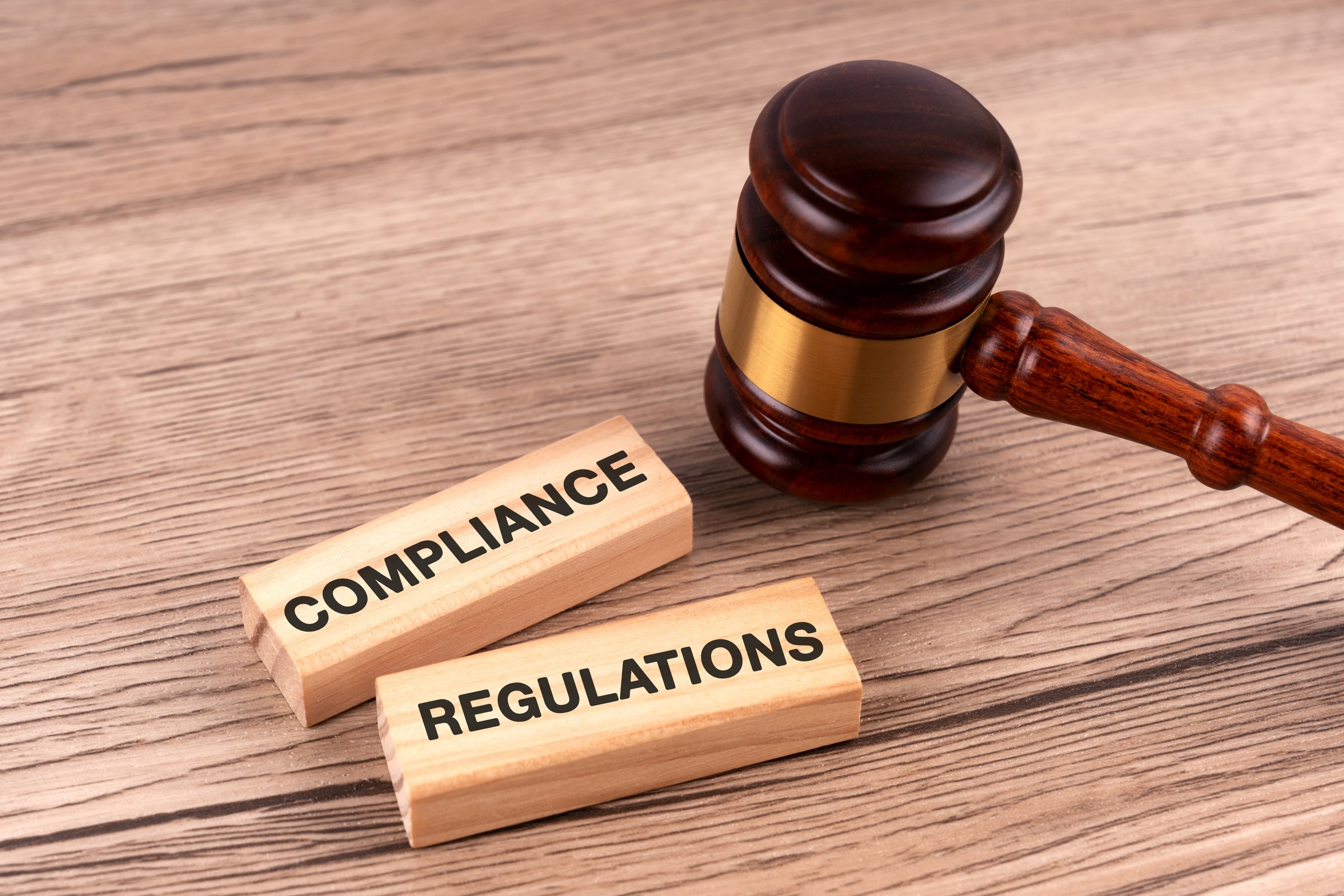 Top view of gavel and wood block with text compliance and regulations