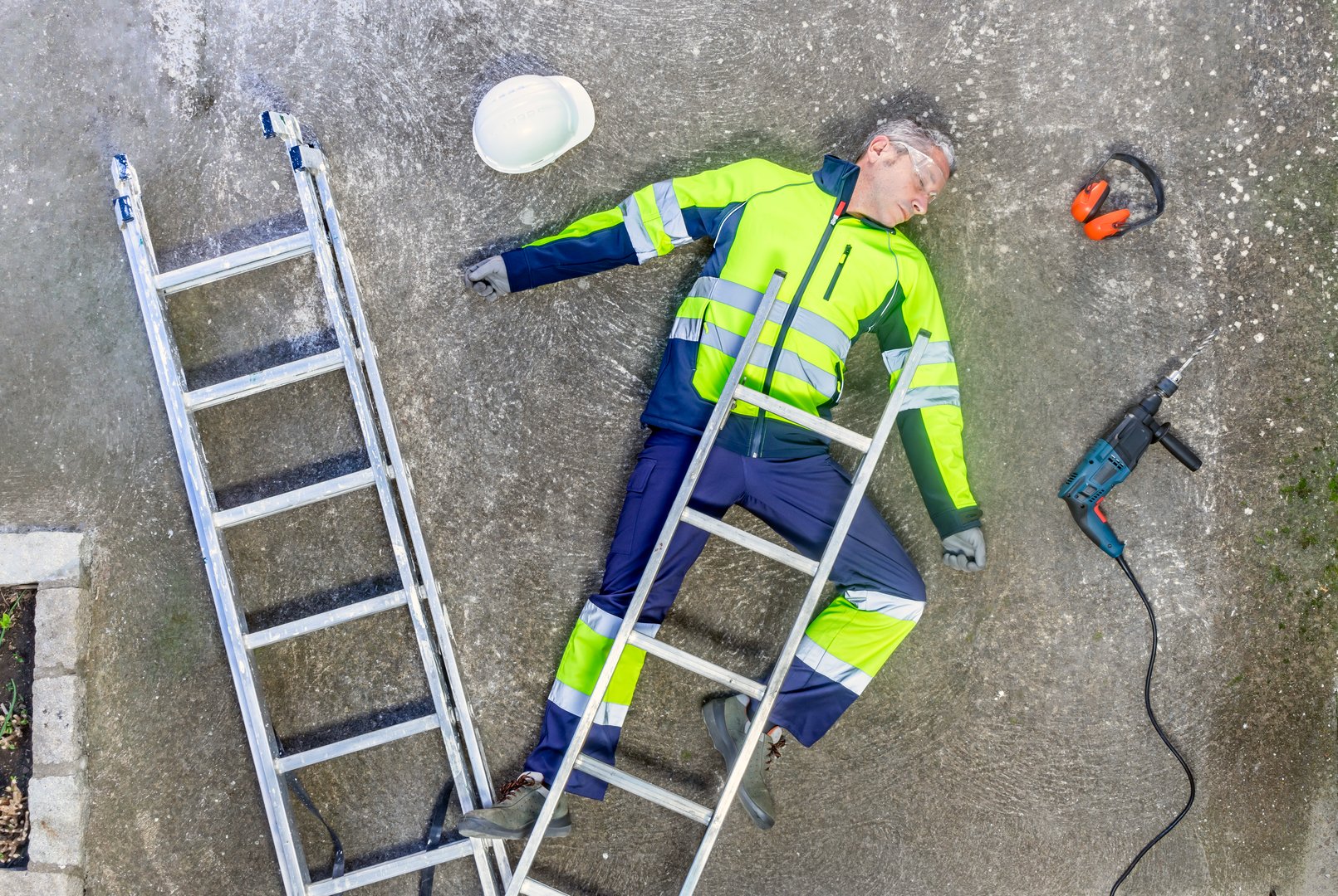Top view of a construction worker lying unconcious on the ground after a workplace accident. Occupational risk prevention. Ppe for health and safety at work.