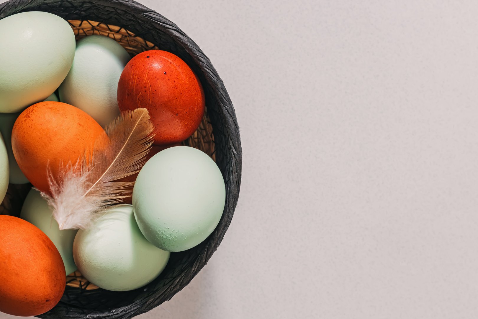 Variety of naturally colored blue and red eggs in a basket, eco natural farmers product