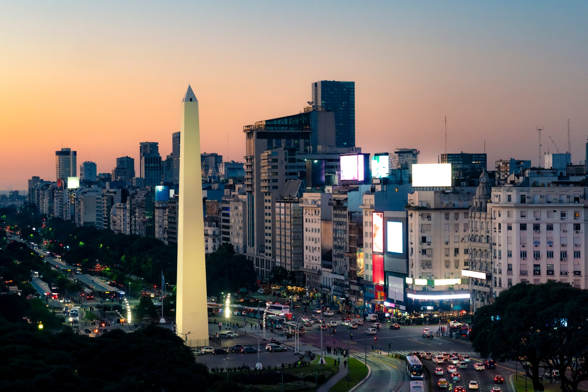 The Obelisk of Buenos Aires stands tall at sunset along 9 de Julio Avenue, symbolizing Argentina's capital with vibrant lights, history, city life and a breathtaking skyline view.