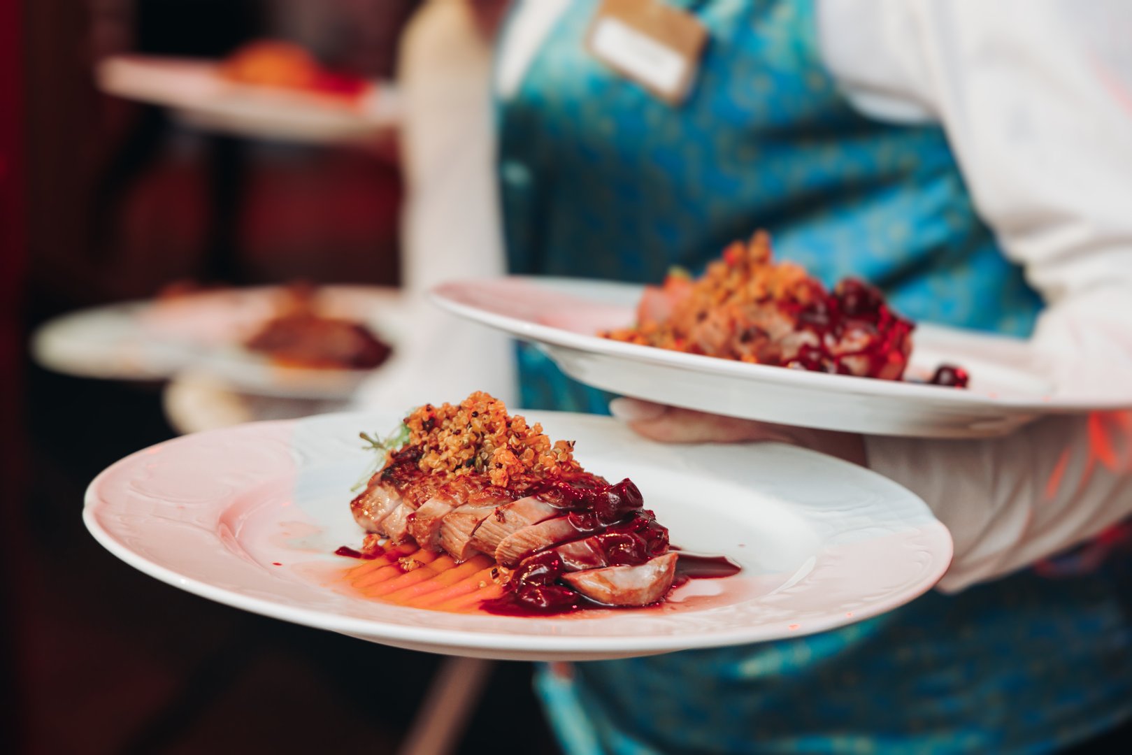 Waiter in uniform serving dishes on party event, server carrying plates with food at the table, catering service on wedding reception, cafe restaurant table service, waiters arranging dinner banquet