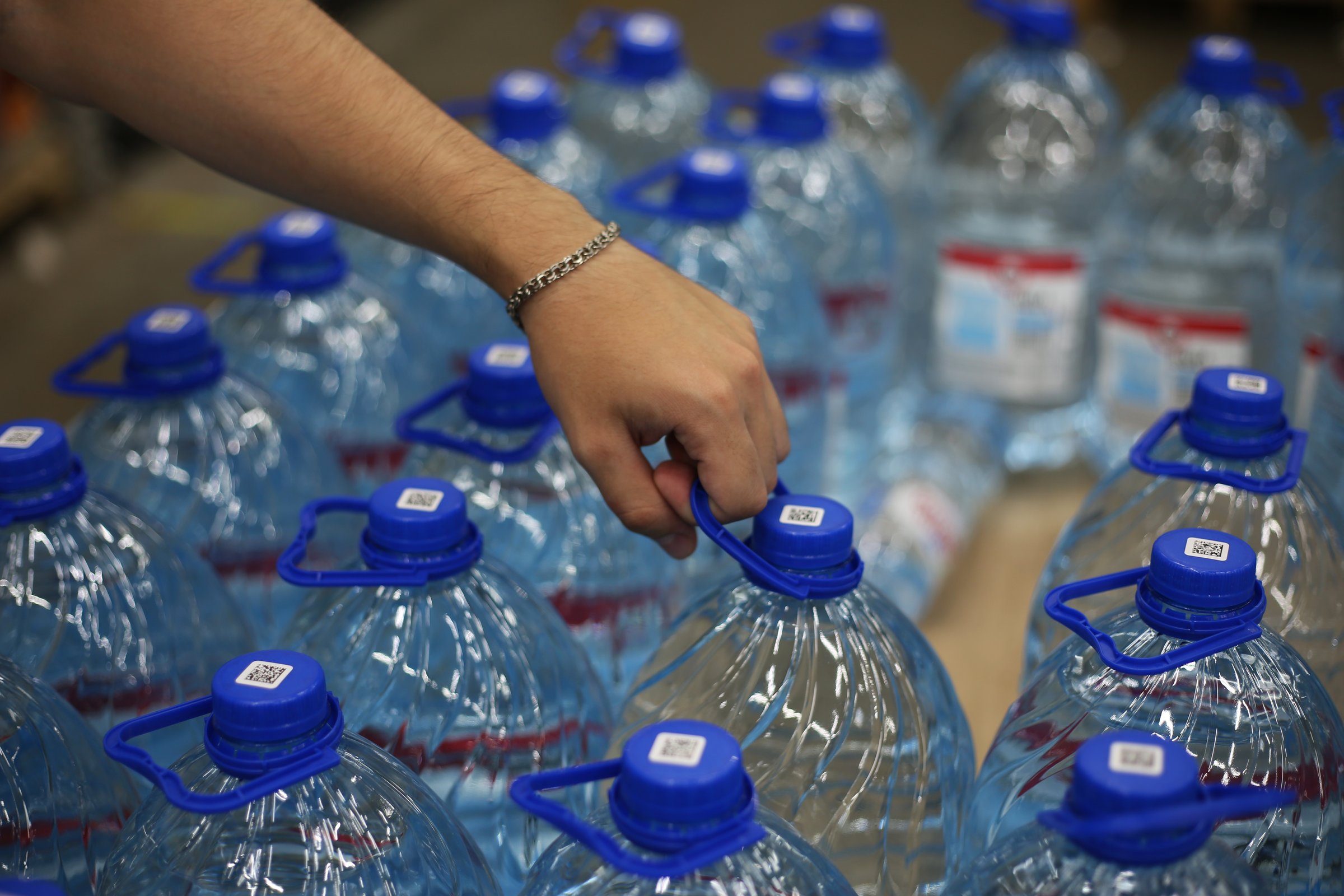 The hand of a young man takes out a five-liter bottle of water in a store. Selection of healthy water from the counter in the grocery store