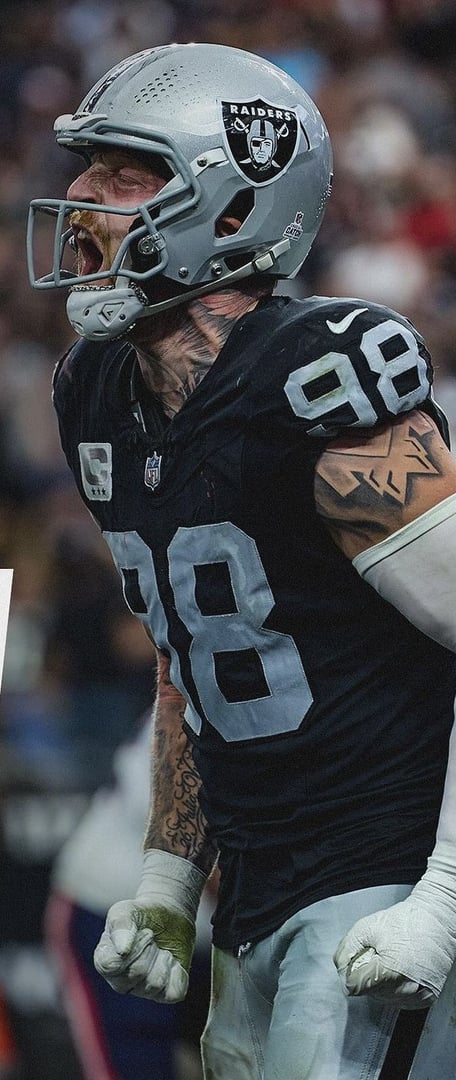 Football player in Raiders uniform and helmet passionately celebrating on the field, wearing number 98.