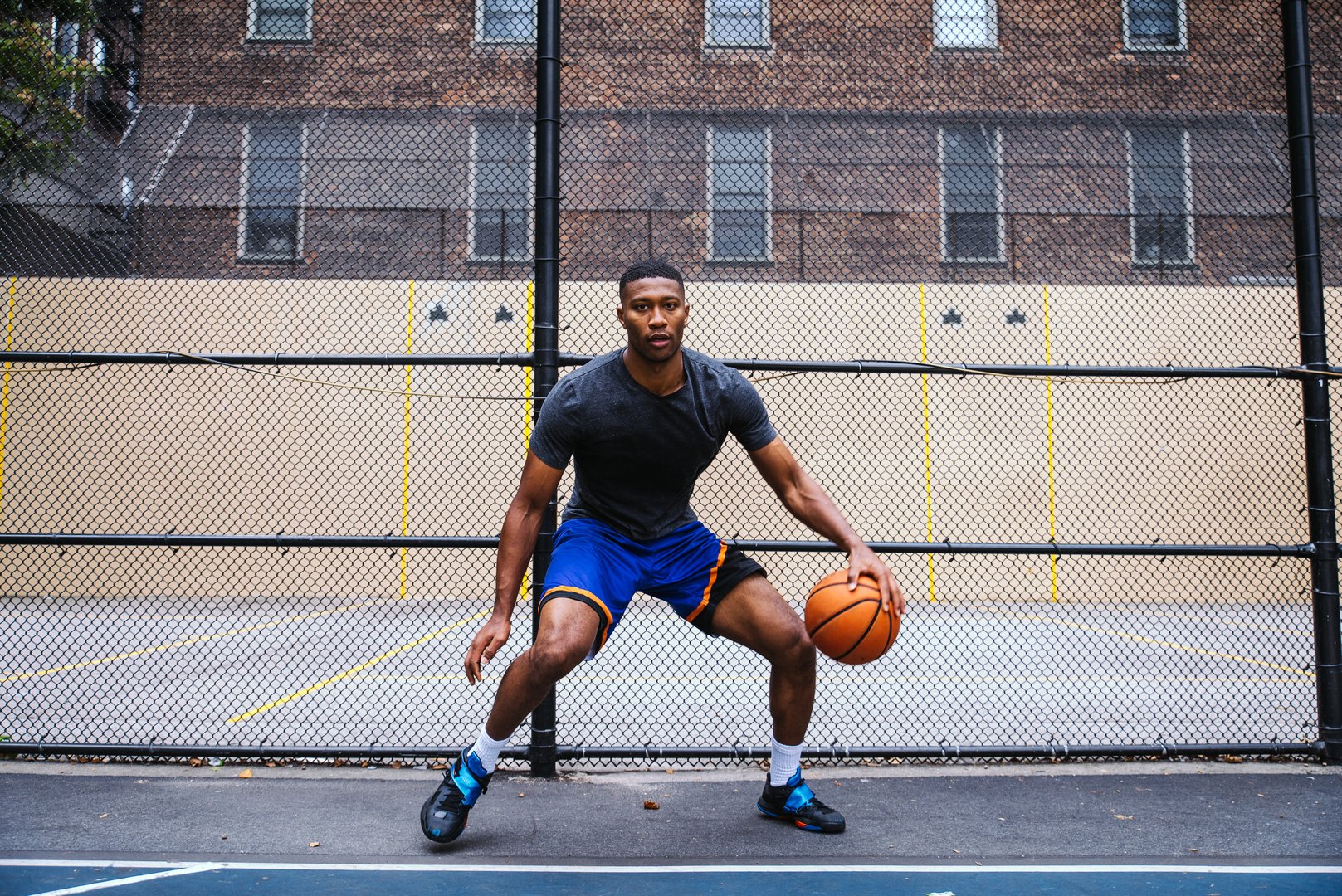 Young Man Playing Basketball Against Chainlink Fence