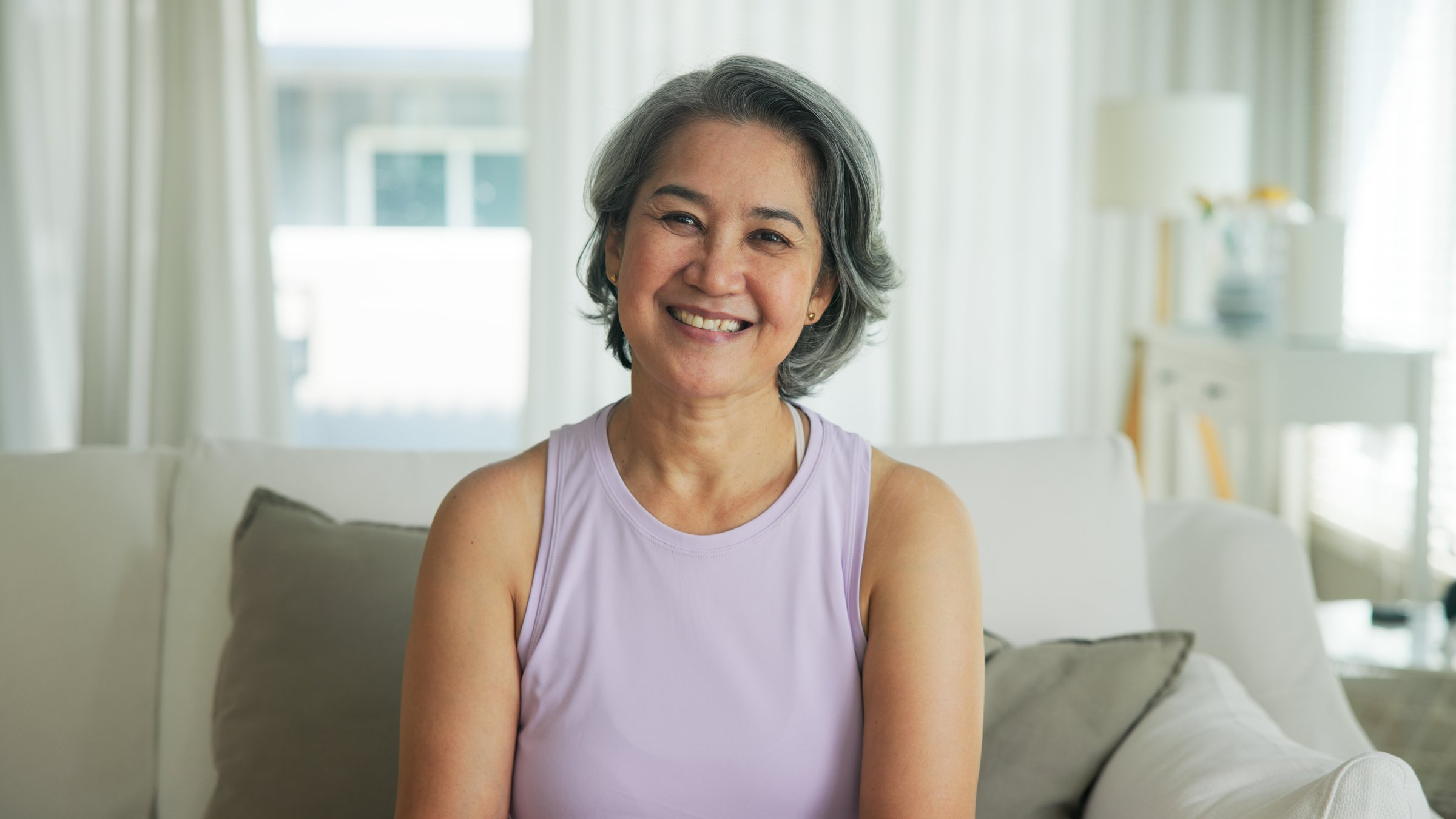 Asia adult active aged people middle age grey hair mom old female joy smile front view look at camera happy face mental health care sit relax at home sofa elder aging life asian single mum parent day.