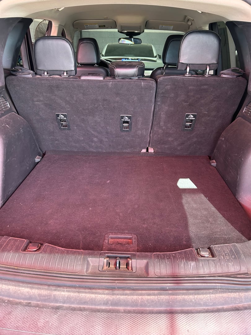 SUV trunk with folded rear seats, showing spacious cargo area and black interior upholstery.