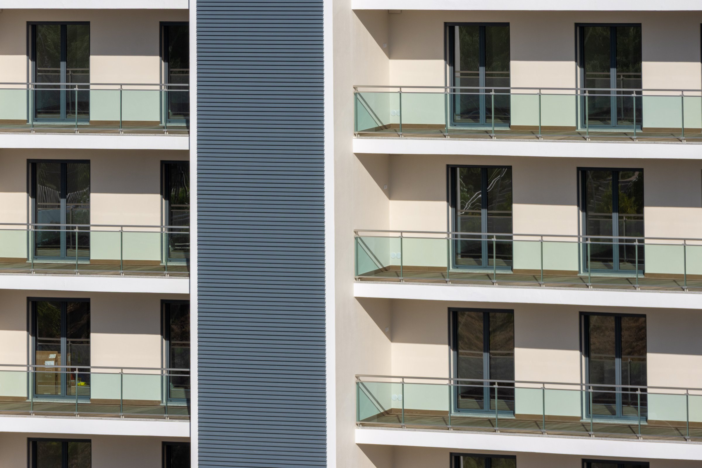Modern residential building facade with balconies and windows, repeating geometric pattern