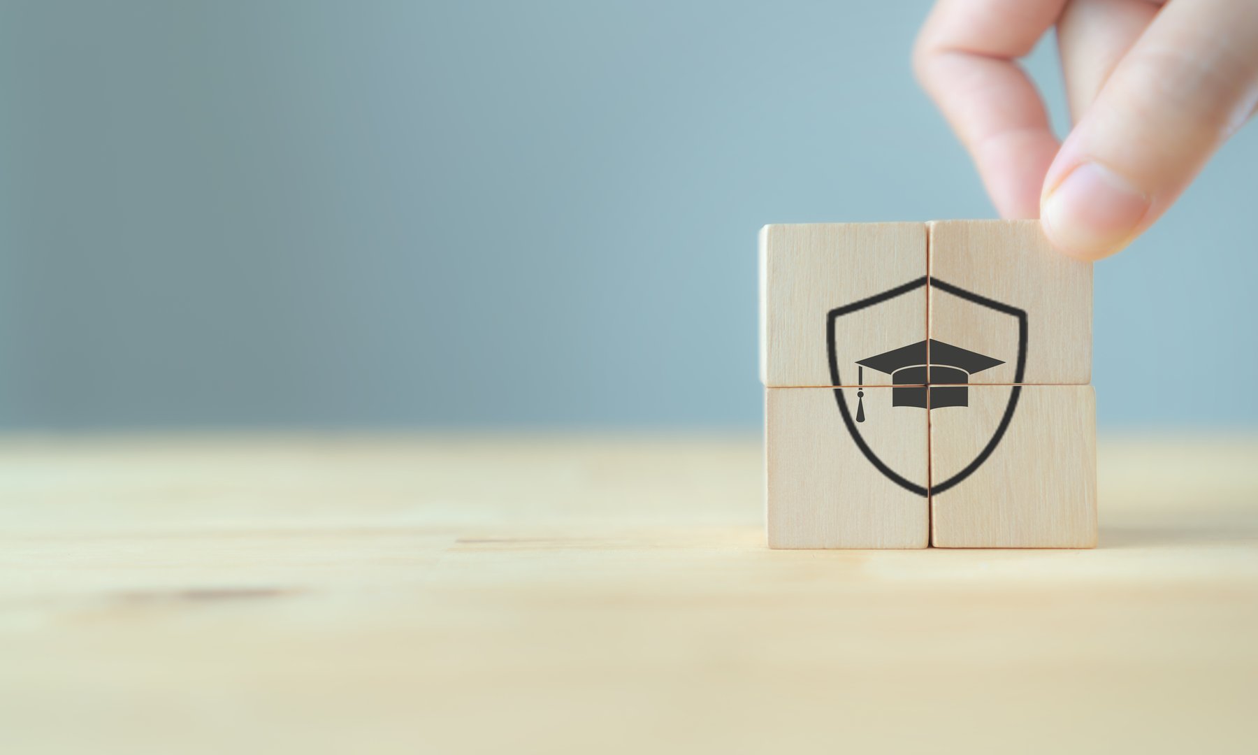 Insurance for education concept. Protection and study, education security sign. The wooden cubes with protection and security of education symbols on beautiful grey background with copy space.