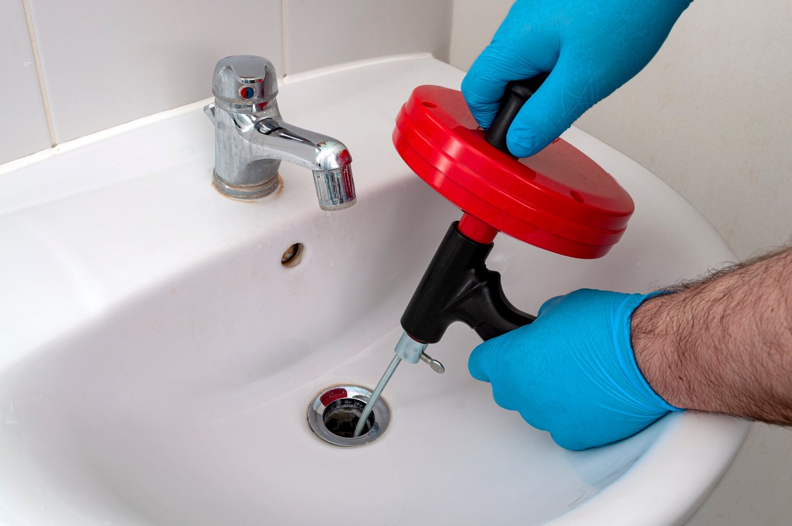 Plumber using drain snake