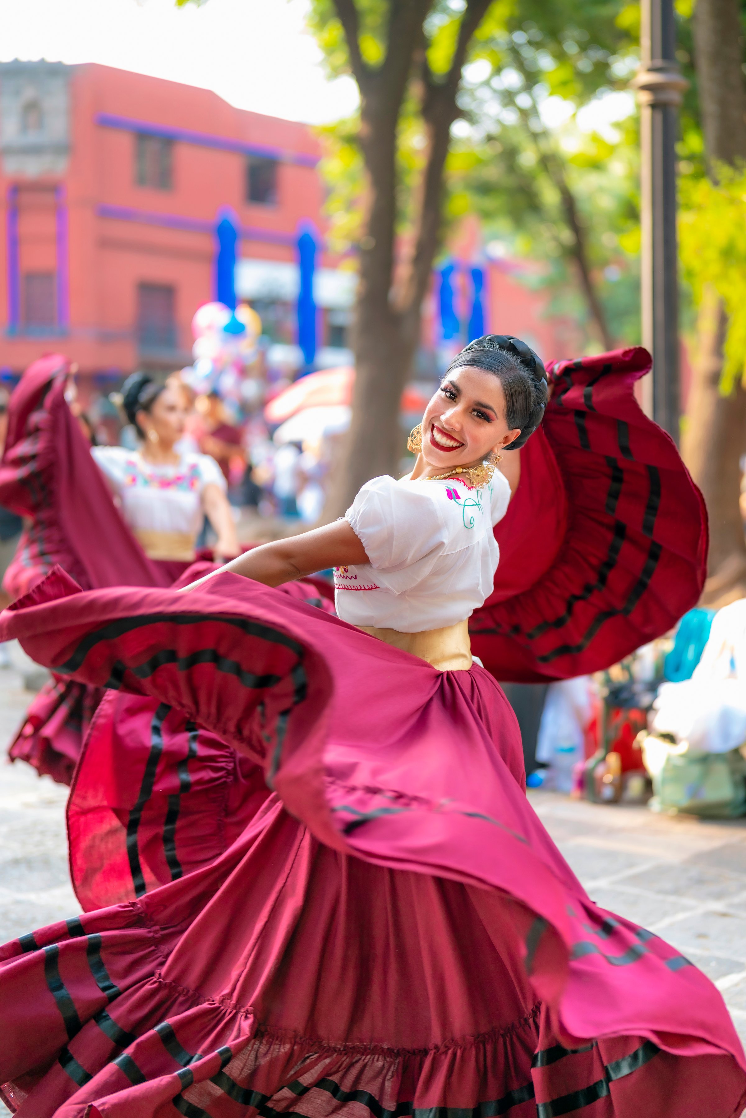 Mexico, Mexico City - June 4, 2024: Young Latina woman in a vibrant traditional dress twirling joyfully during a performance in Coyoacan, Mexico City, Mexico.