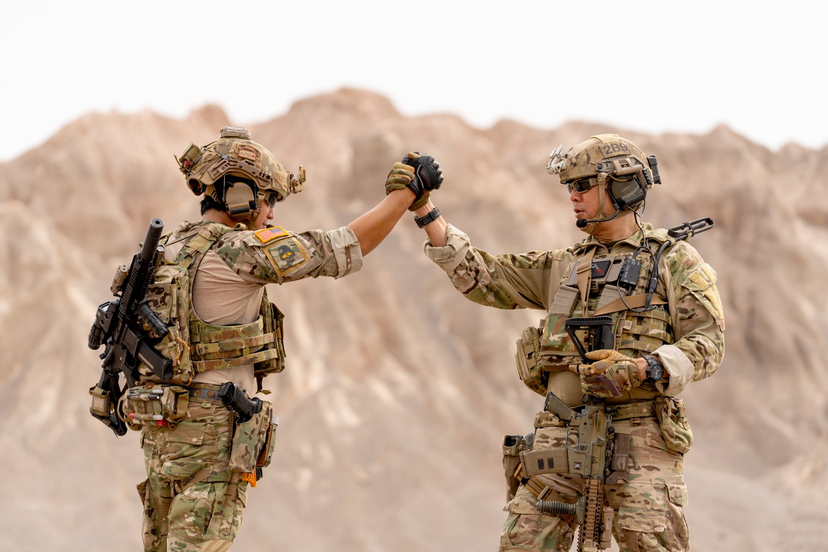 Two of soilders or militaries with war suit and gun holding hands together during outdoor practice.
