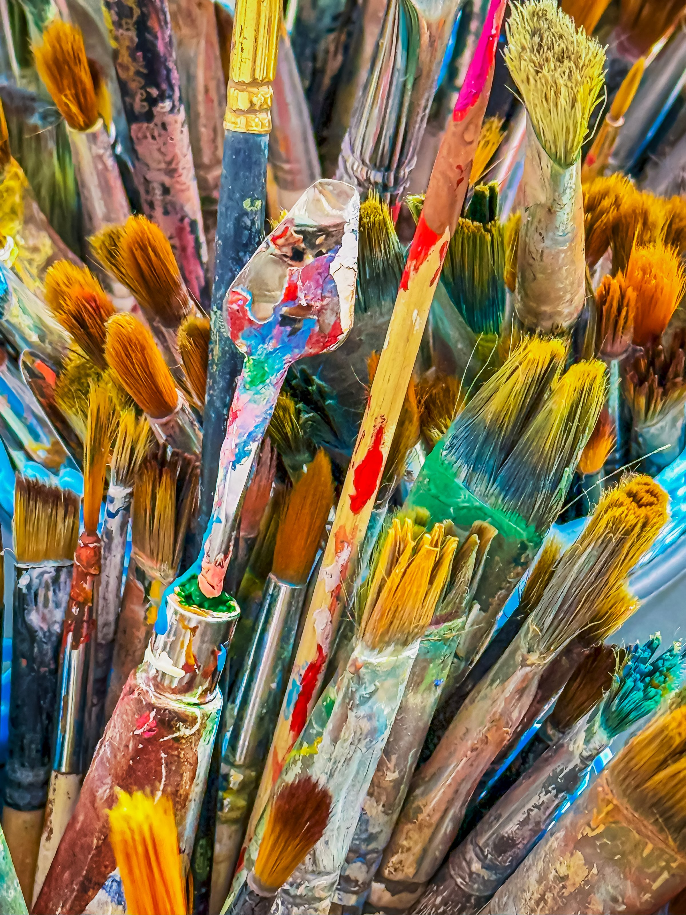 Colorful assortment of paintbrushes in an artist's studio during a creative session. Vibrant collection of various paintbrushes of artist. Brushes are dipped in colorful paints, creativity concept