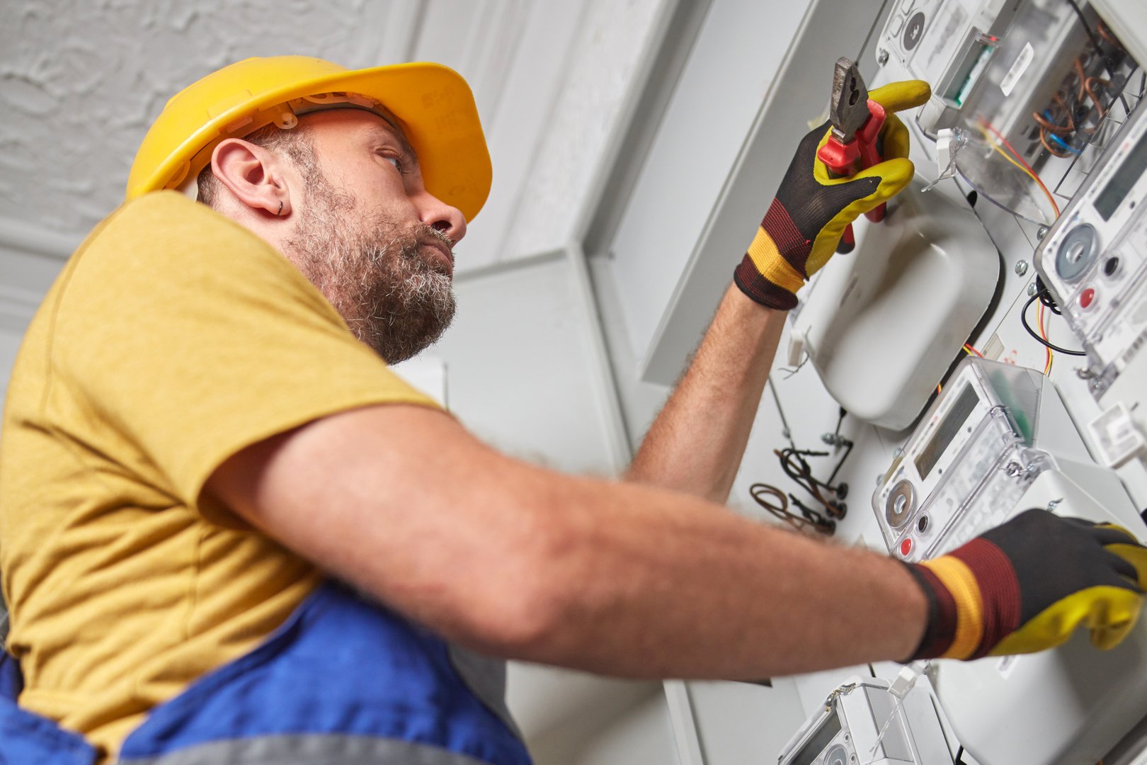 Technician working on a electricity power meter station in a building.