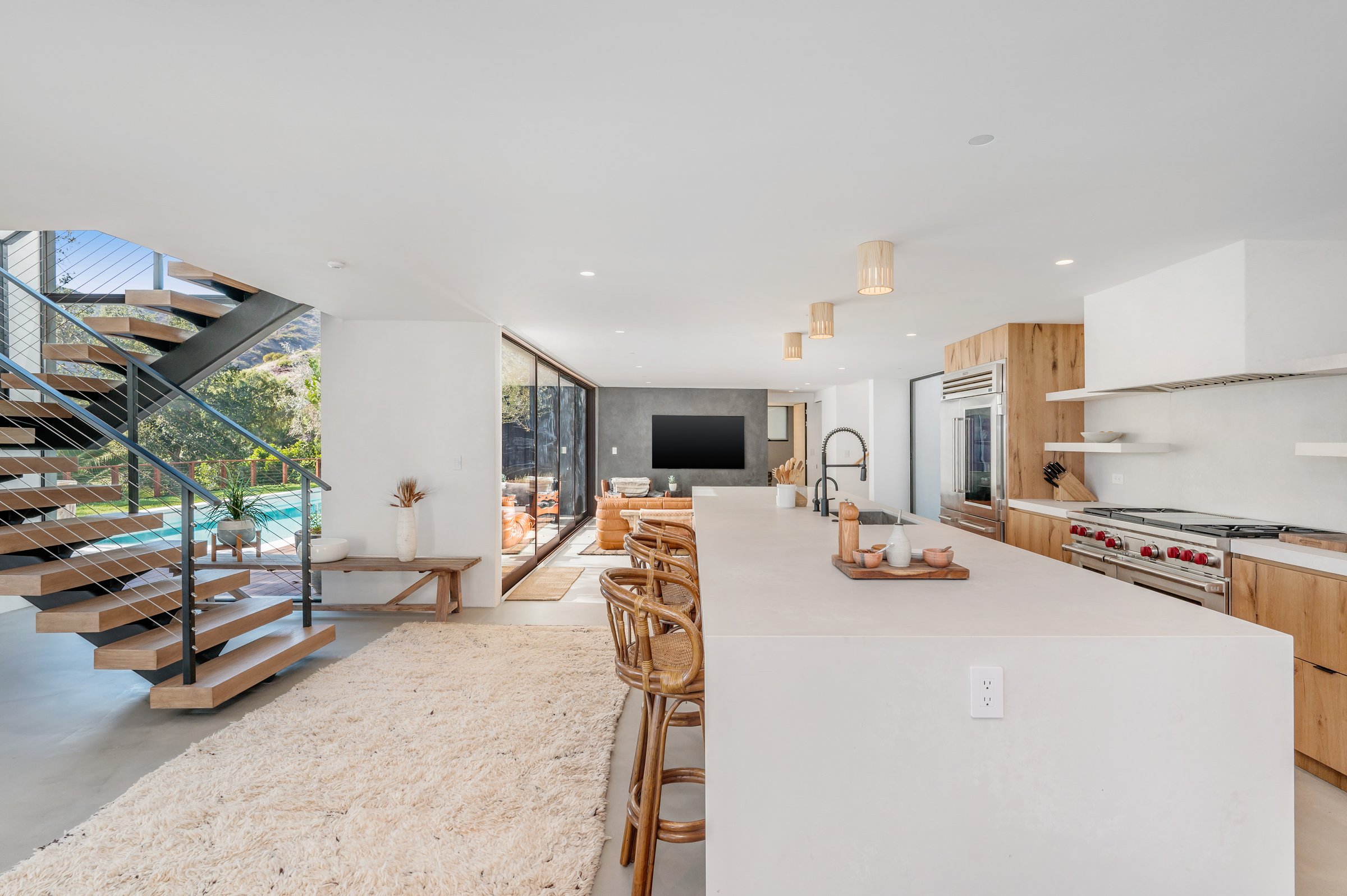 Spacious modern kitchen with stainless steel appliances and wooden staircase
