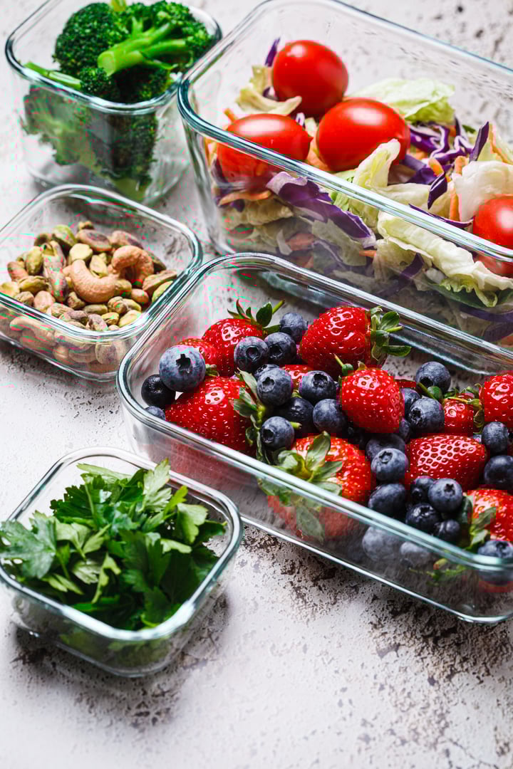 Healthy vegan food preparations for a week in glass containers, close-up. Vegetables, nuts, berries in boxes.