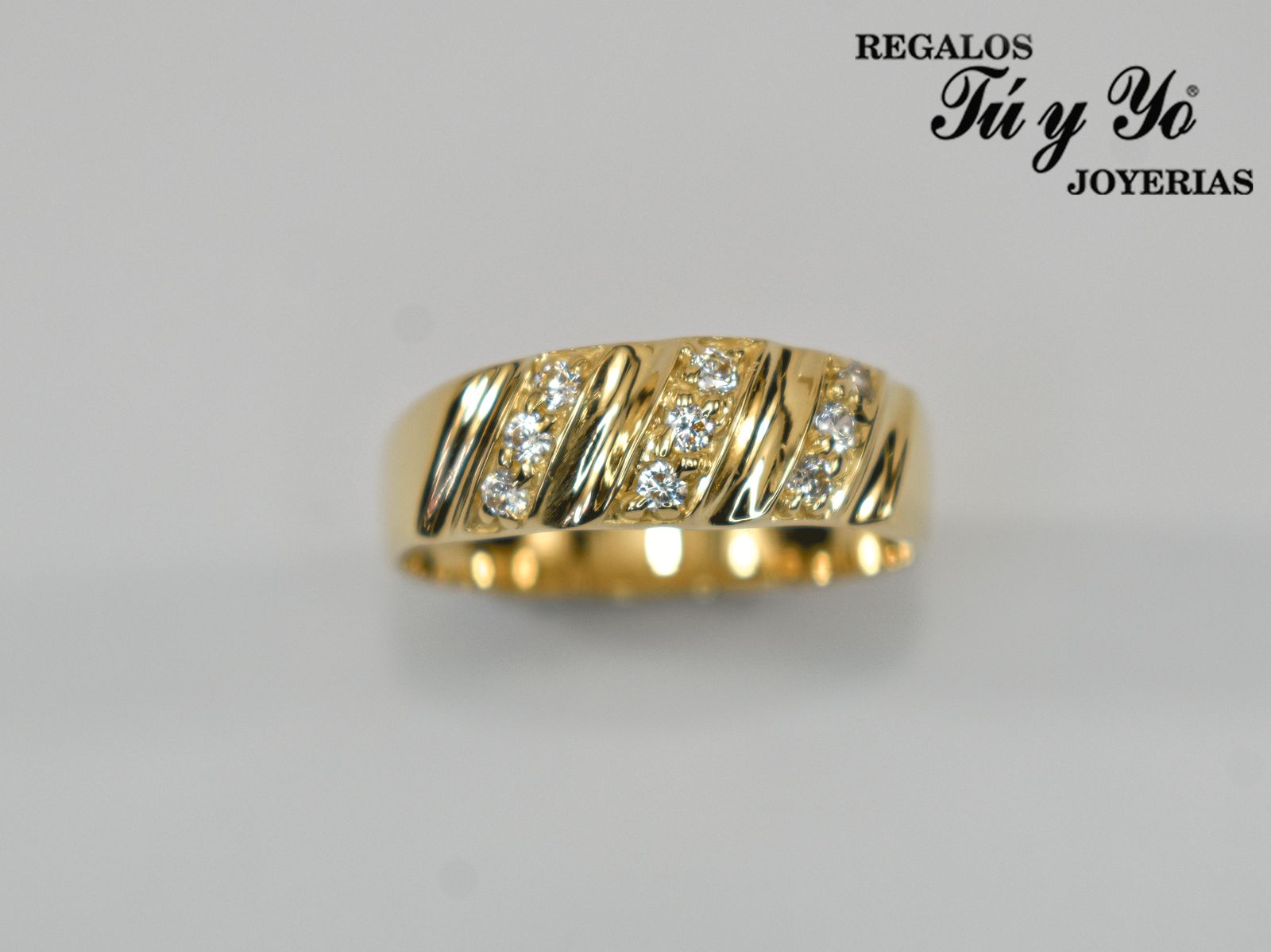 Gold ring with diagonal grooves and embedded diamonds, against a gray background, with a jewelry store logo at the top.
