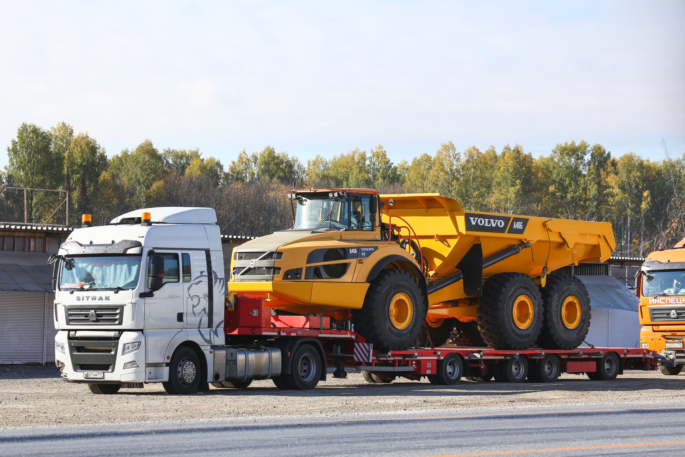 Chelyabinsk region, Russia - September 23, 2023: Chinese semitrailer truck CNHTC Sitrak C7H ZZ4186 carrying the articulated dump truck Volvo A40G at an interurban road.