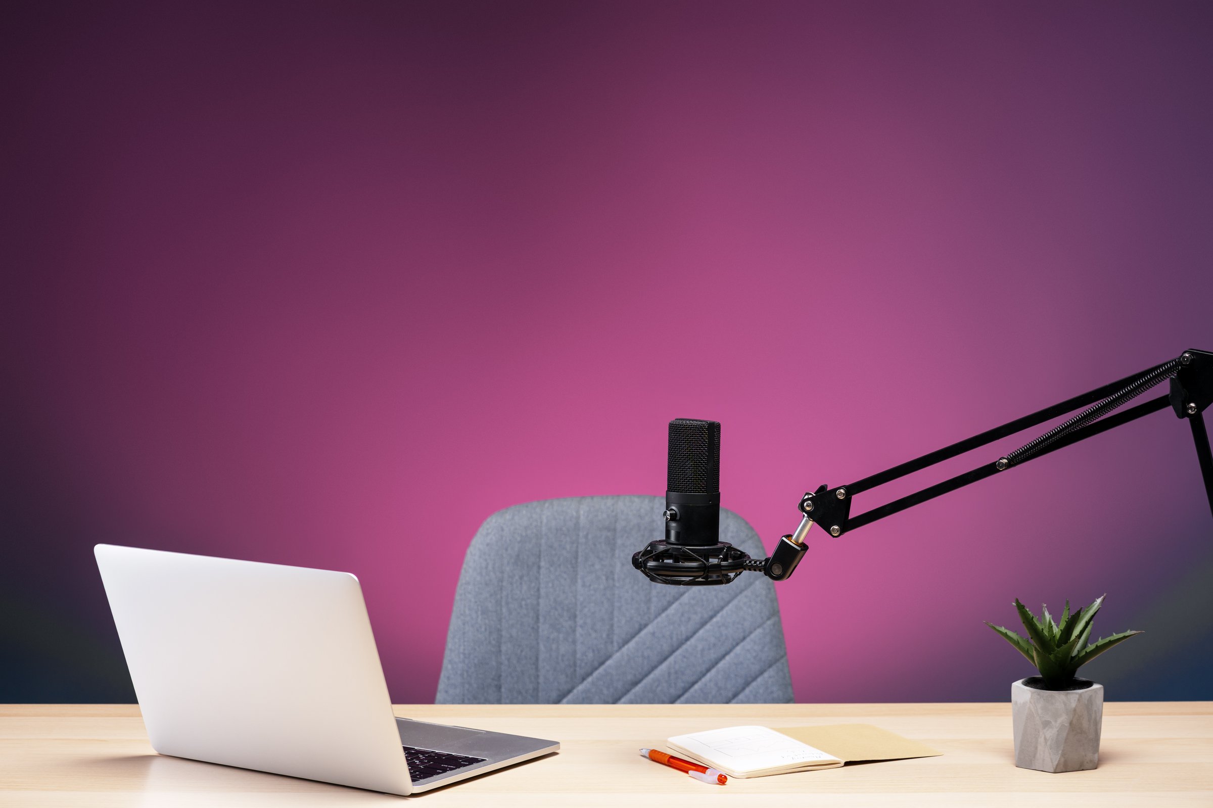 Professional microphone, laptop, and notebook arranged on a desk, ready for a recording session in a home studio setting, creating a productive and creative workspace. Online technology concept
