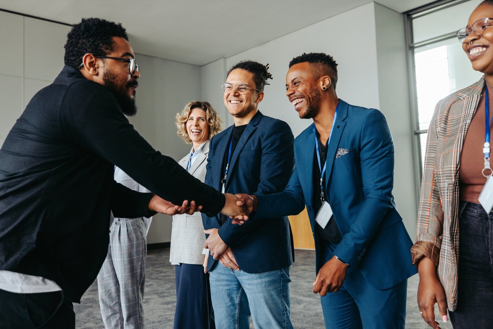 Diverse group of professionals greeting each other with handshakes at a corporate conference event in an office setting.