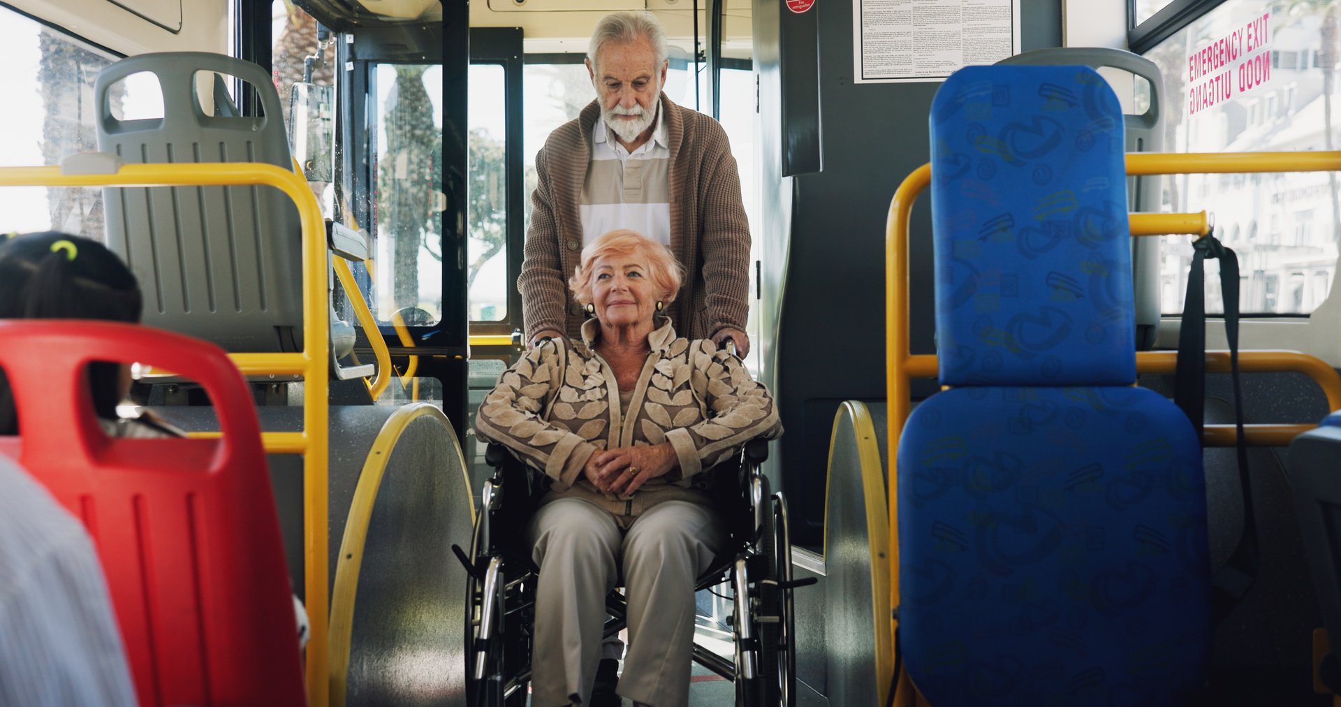 Elderly woman, wheelchair and transport in bus with man, push and helping hand for travel in town. Senior couple, support and person with disability, mobility aid and retirement with trip in city