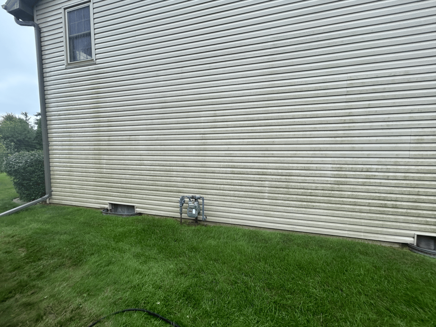 House exterior before pressure washing showing dirt and grime