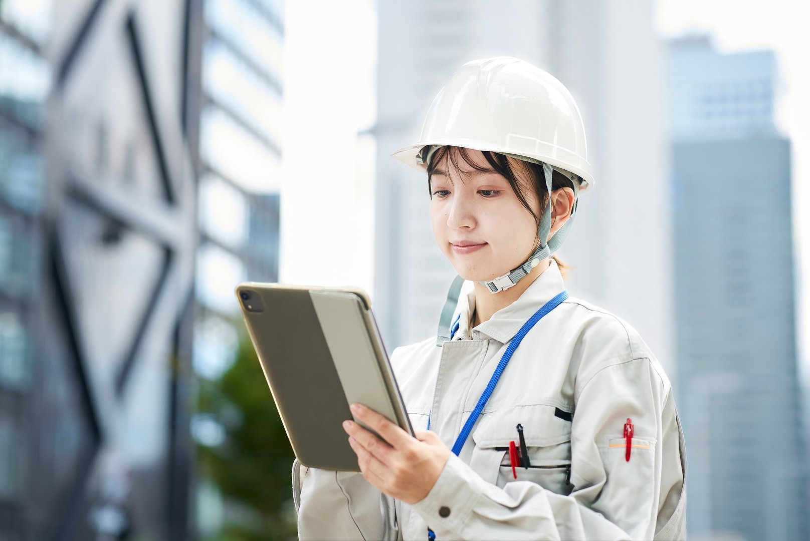 A young woman wearing work clothes and a helmet outdoors