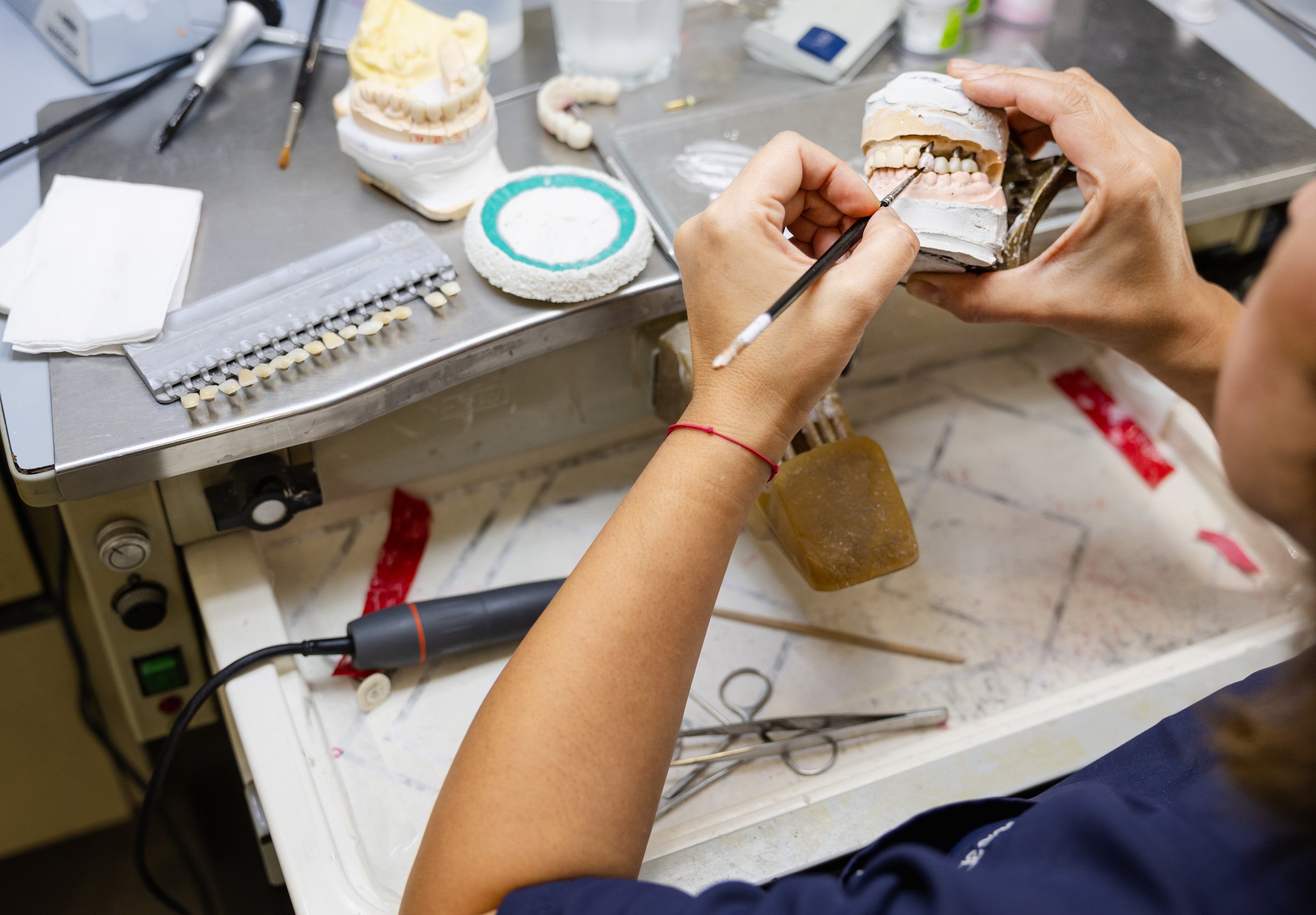 Detailed view of a dental technician restoring a dental mold at the workbench.