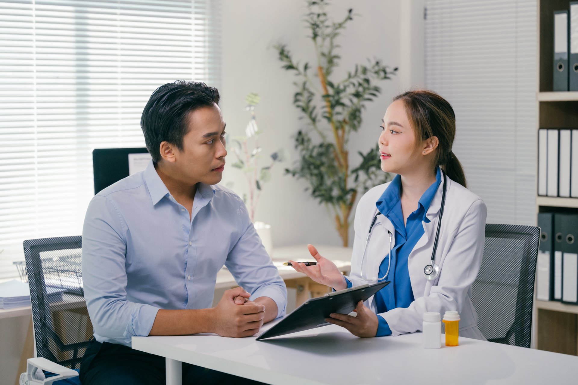 Young female doctor engaging in a detailed discussion with her male patient about his diagnosis during a consultation in a bright, modern medical office, fostering trust and understanding