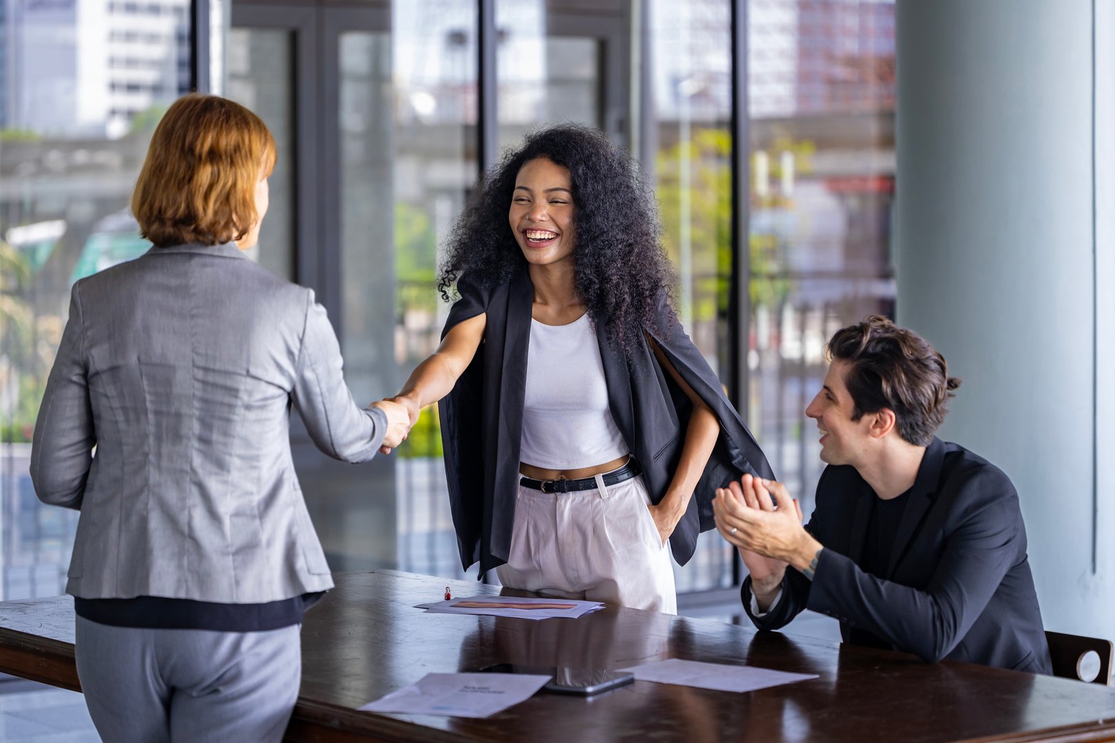 Team of diversity business people having agreement and handshake deal over new strategic strategy project on investment real estate with recognition and applause from other colleagues for partnership