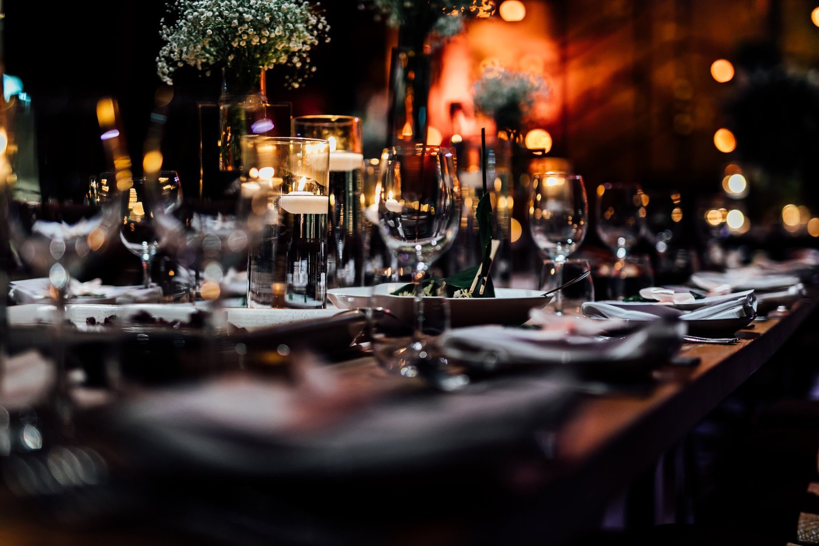 Luxury table settings for fine dining with and glassware, pouring wine to glass. Beautiful blurred background. Preparation for holiday wedding. Fancy luxury restaurant.