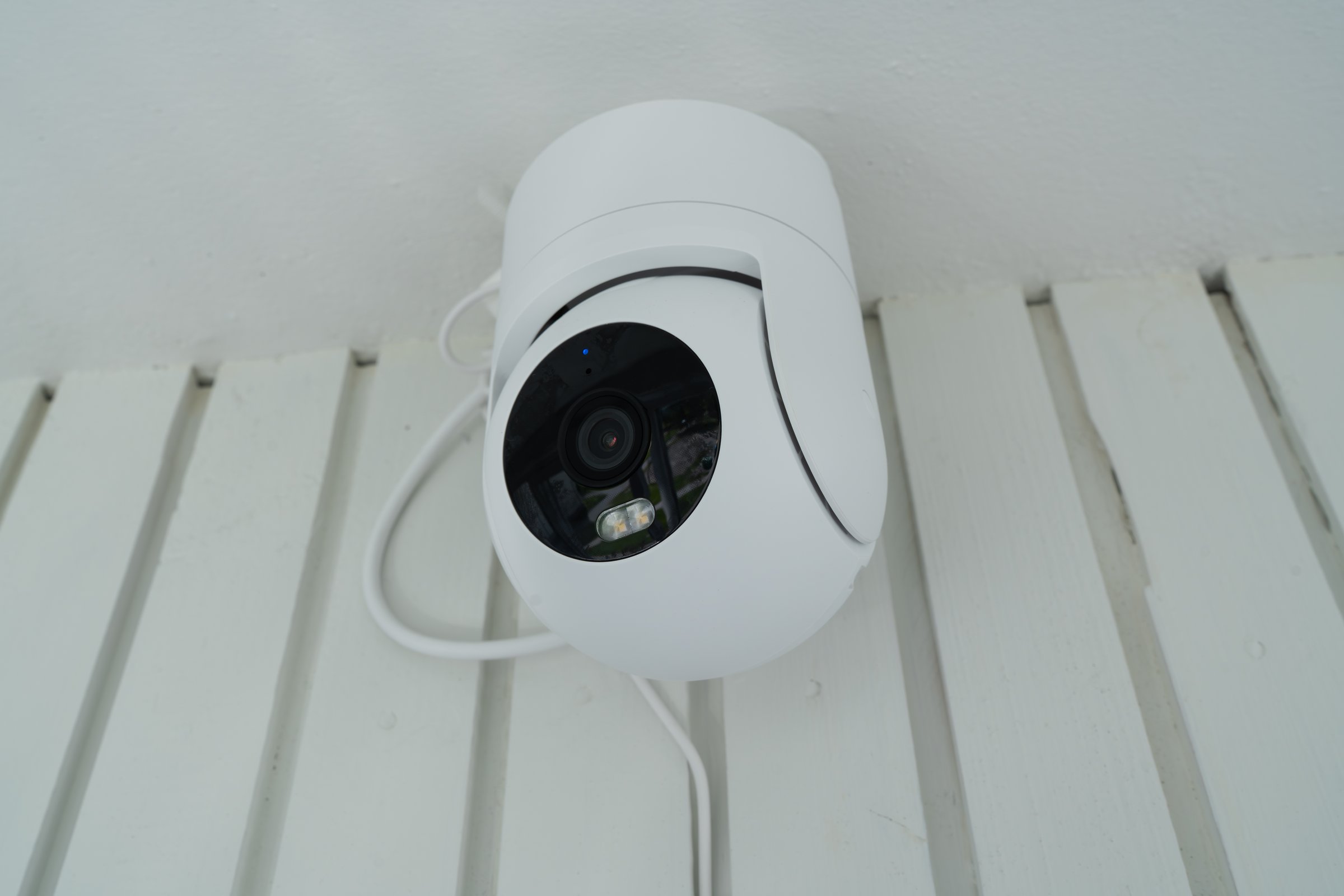 Modern white PTZ IP camera installed on a ceiling. Smart home technology concept for surveillance, safety, and security.