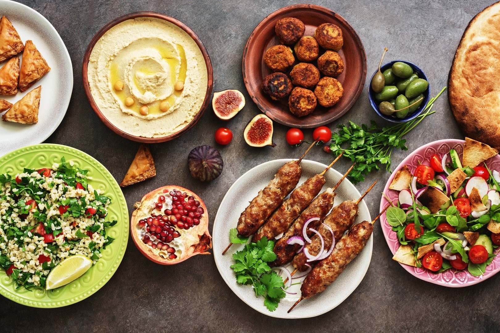 Arabic and Middle Eastern dinner table. Hummus, tabbouleh salad, Fattoush salad, pita, meat kebab, falafel, Znoud el Sit, pomegranate. Set of Arabian dishes.Top view, flat lay.