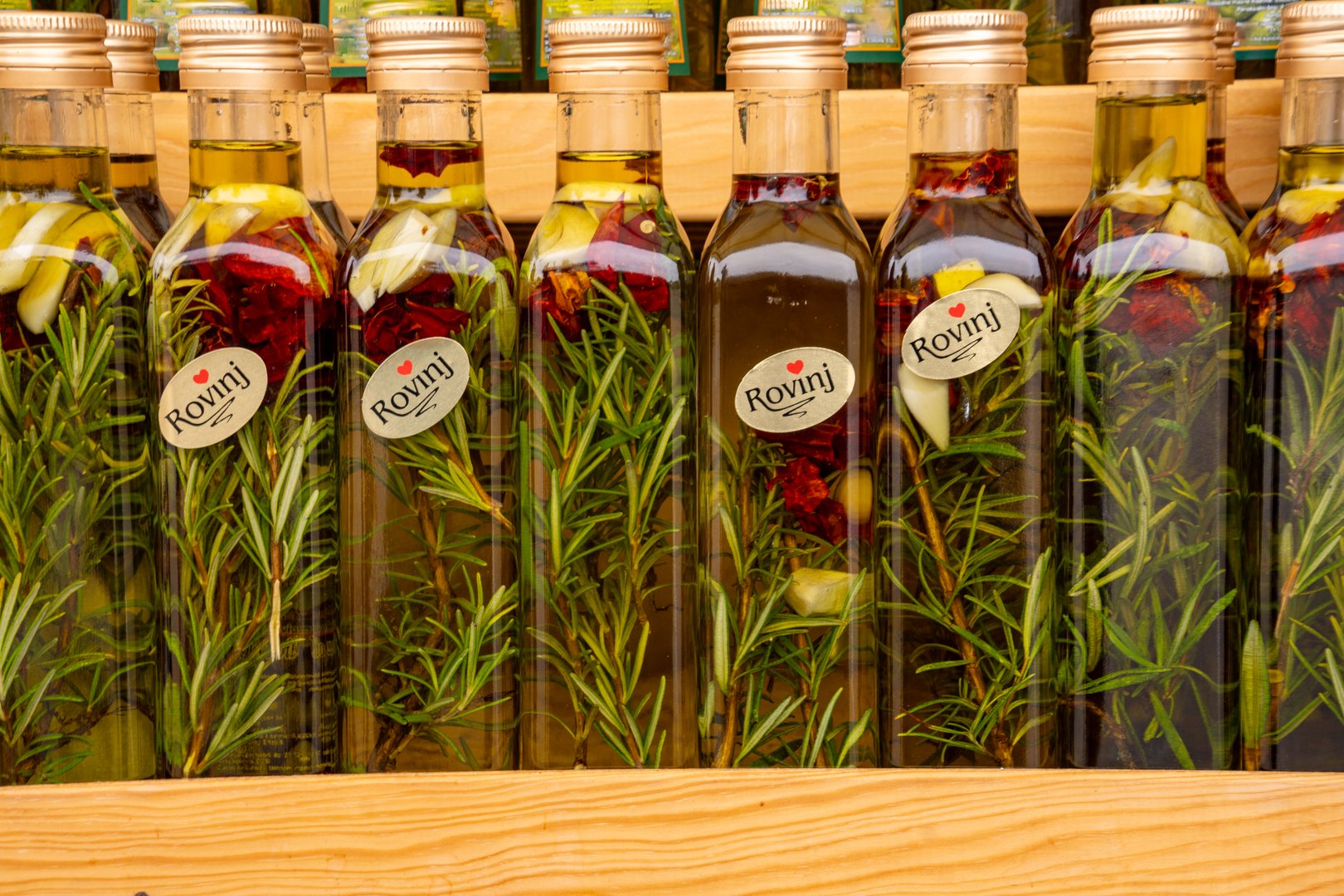 Display of olive oil flavored with herbs and spices in bottles labeled "Rovinj" at the market in Rovinj in Istria, Croatia. A local specialty