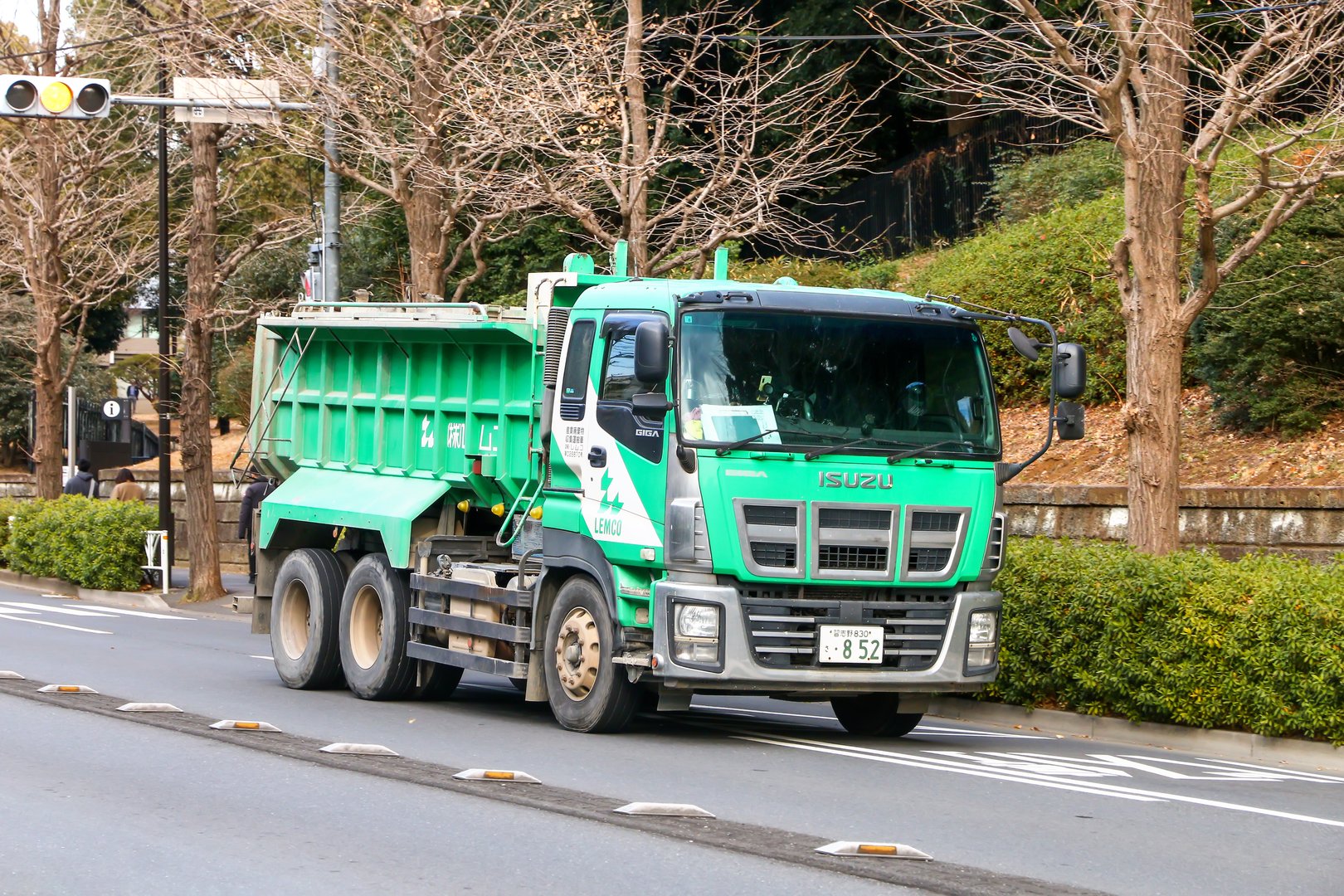 Tokyo, Japan - January 15, 2025: Bright green heavy-duty dump truck Isuzu Giga in the city street.