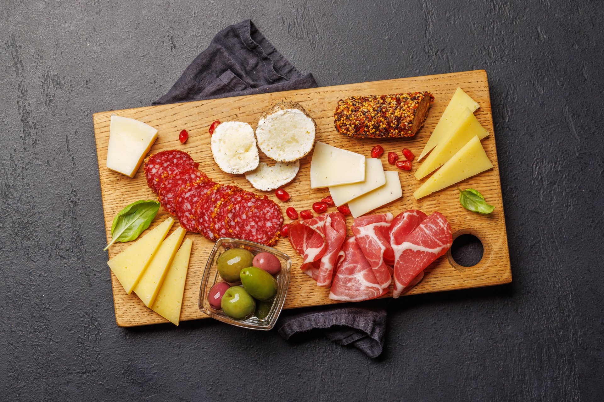Assorted cheeses and cured meats on a wooden board, classic antipasti platter for wine and gatherings