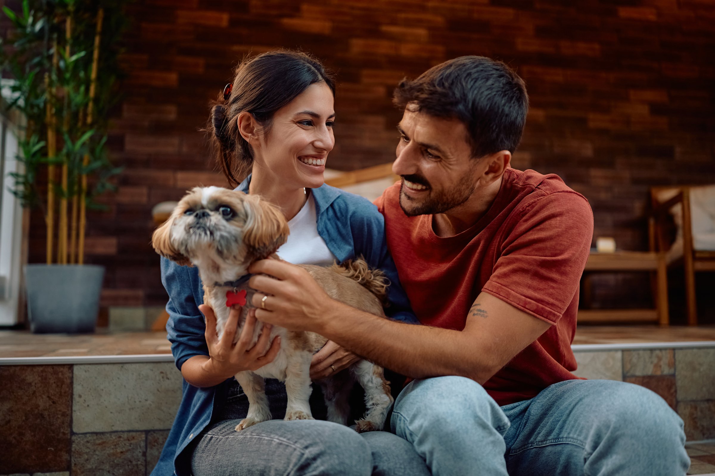 Happy pet owners with dog enjoying on their porch.
