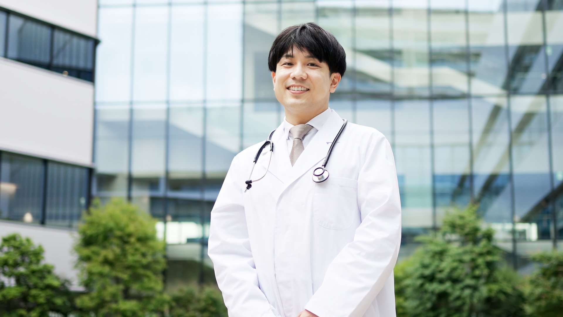 Smiling Asian male doctor standing